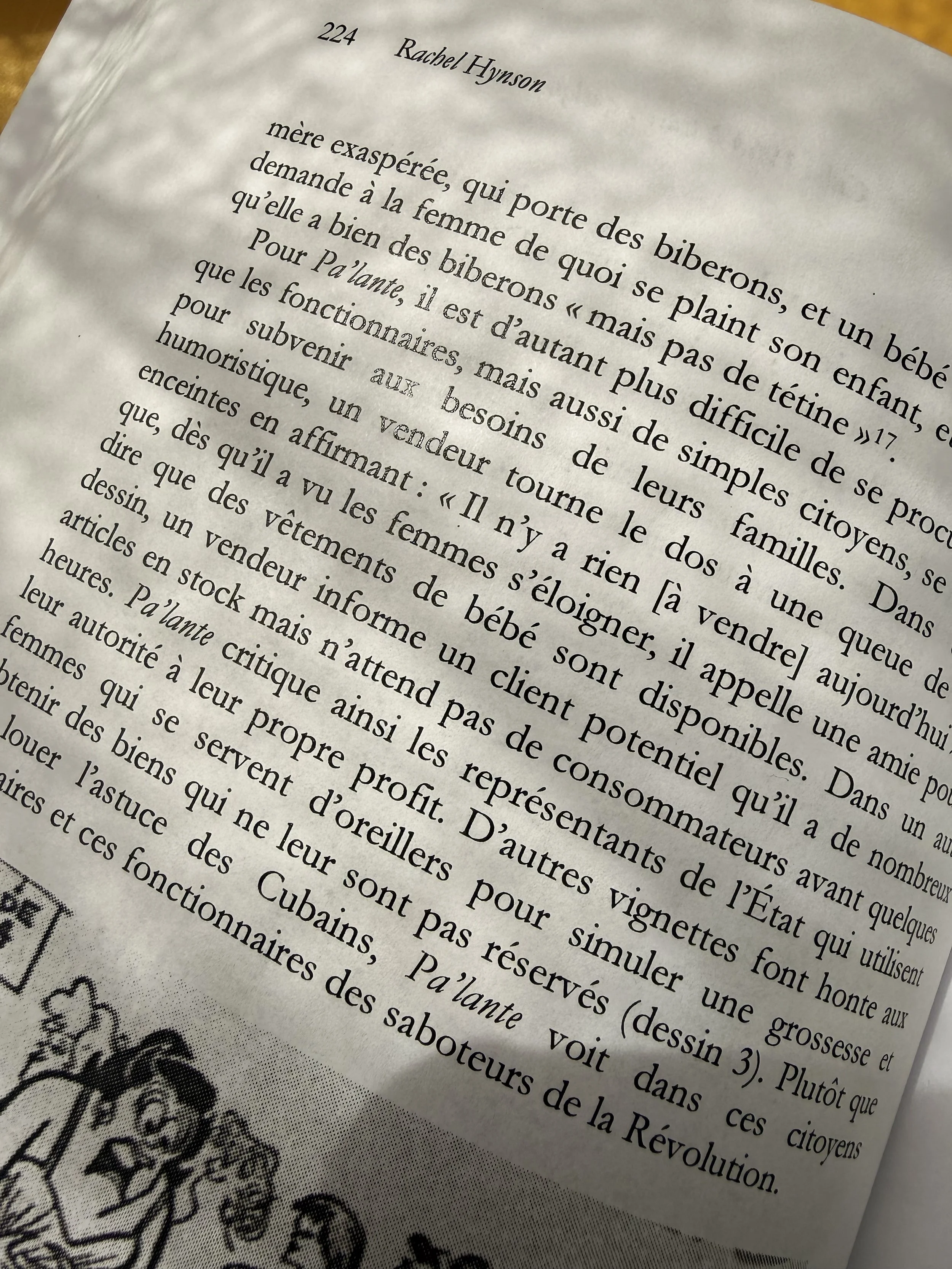 Close-up of a printed page, written in French, with a hint of the drawing at the bottom of the page of a gathering of people.