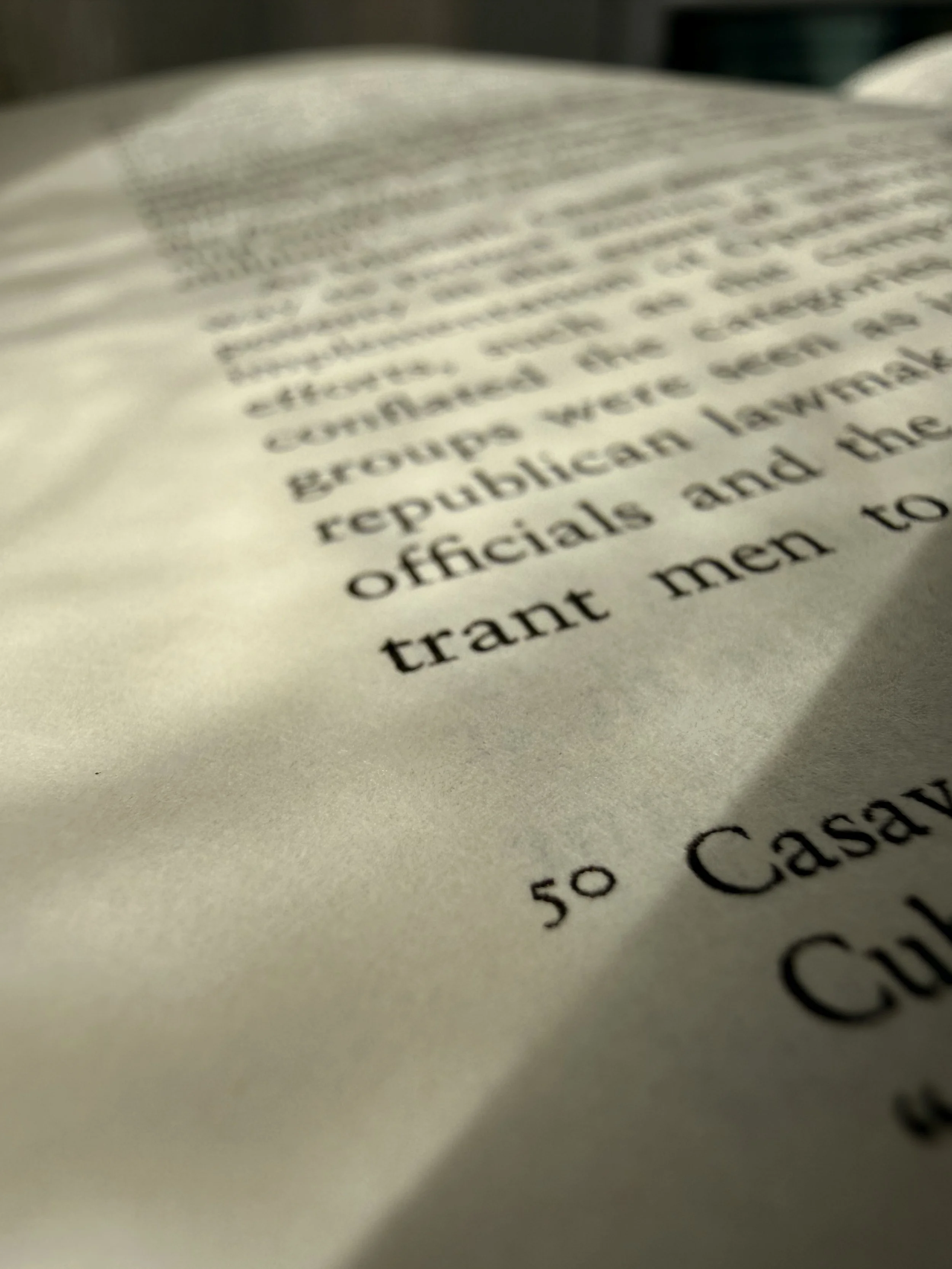 Close-up of a printed book page; a shadow is cast at an angle by the light.