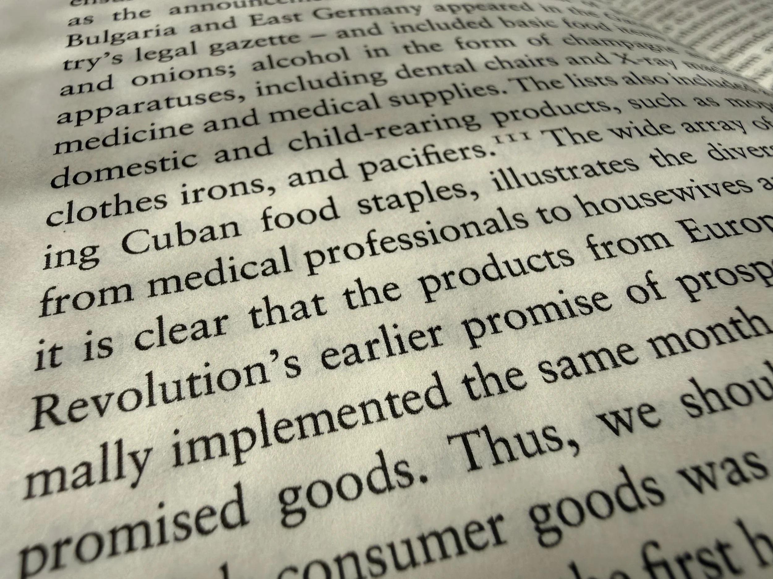 Close-up of printed text on a book page, showing words like 'revolution,' 'medical,' and 'products." Mottled shadows spot the page.