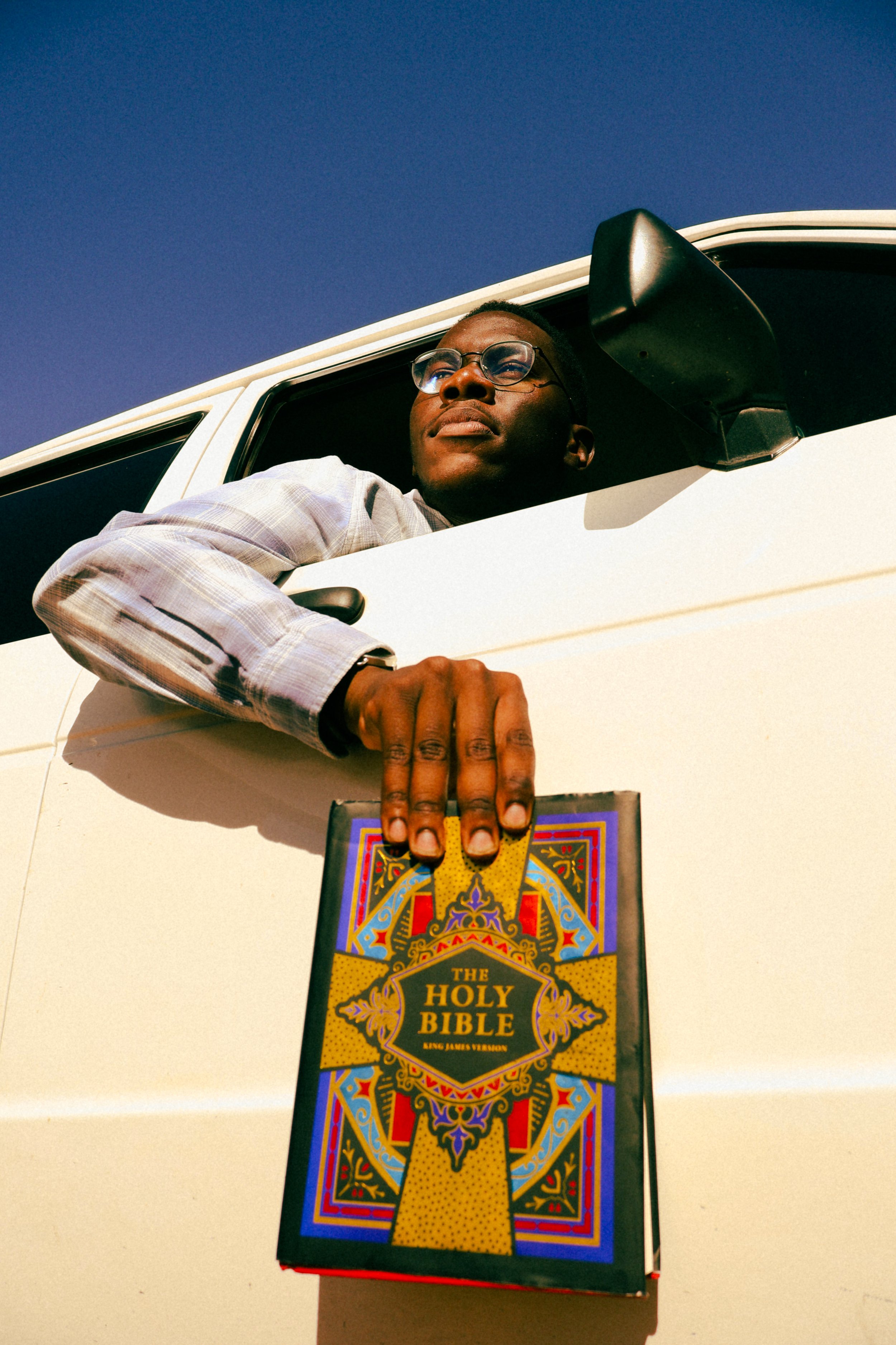 Photograph taken by Kim Kambinda of Eleazar Mwakipesile sitting in his car with a bible in his hand