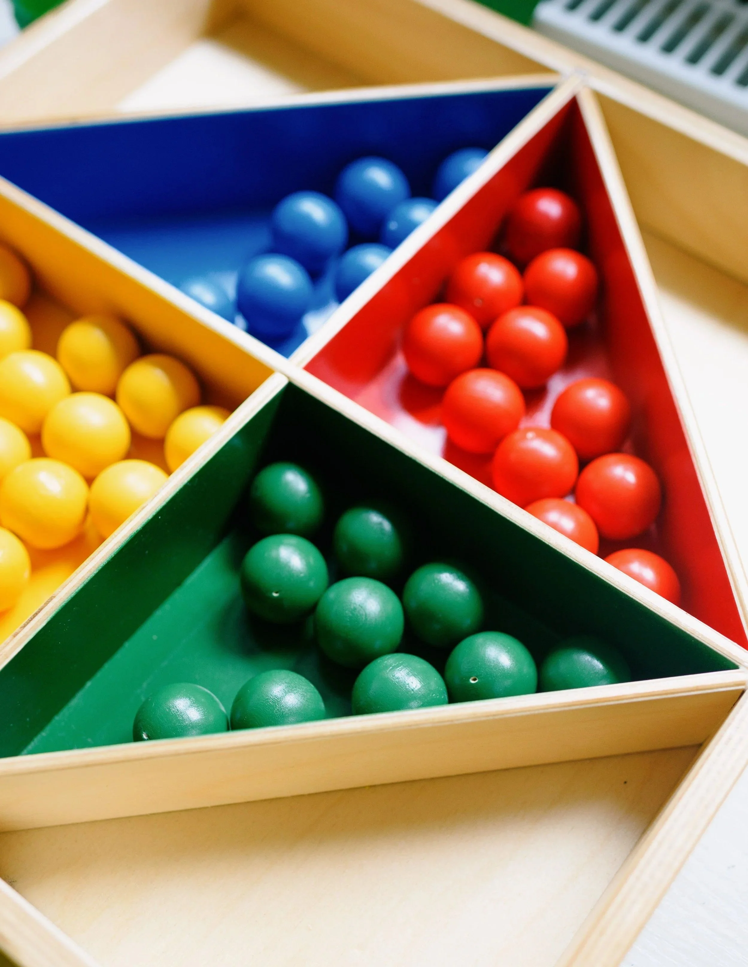 Colorful wooden triangle puzzle with colored balls inside each compartment, including blue, red, yellow, and green balls.