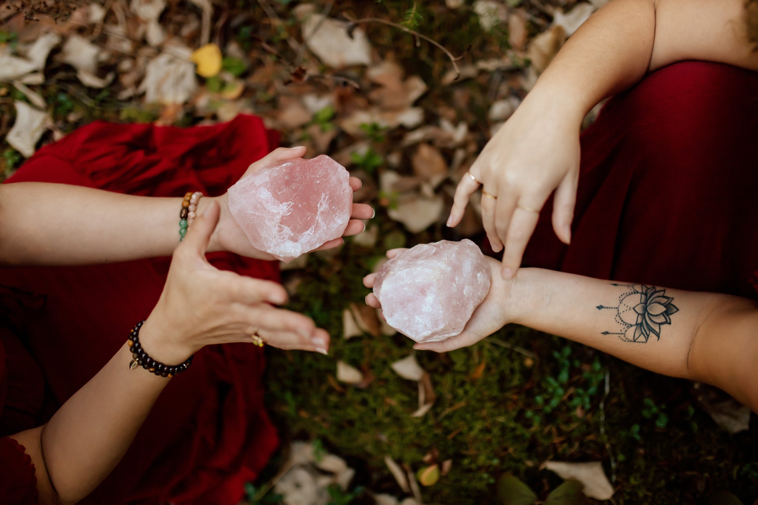 Two people holding large pink Himalayan salt rocks outdoors, with fallen leaves on the ground.