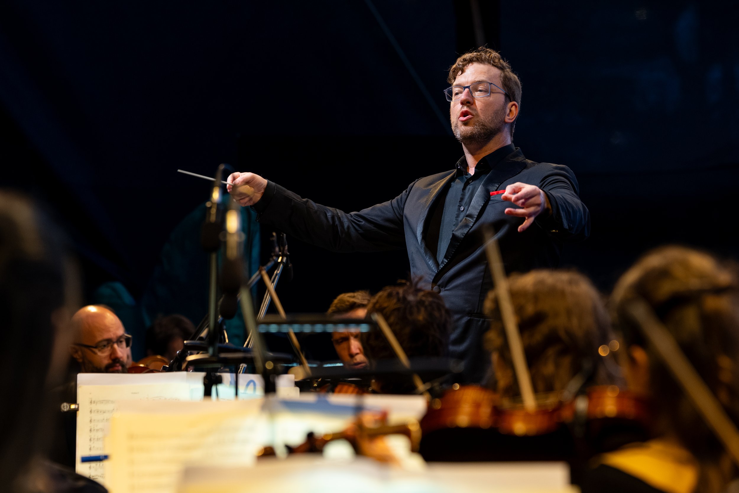 Benjamin Bayl leading an orchestra during a live performance