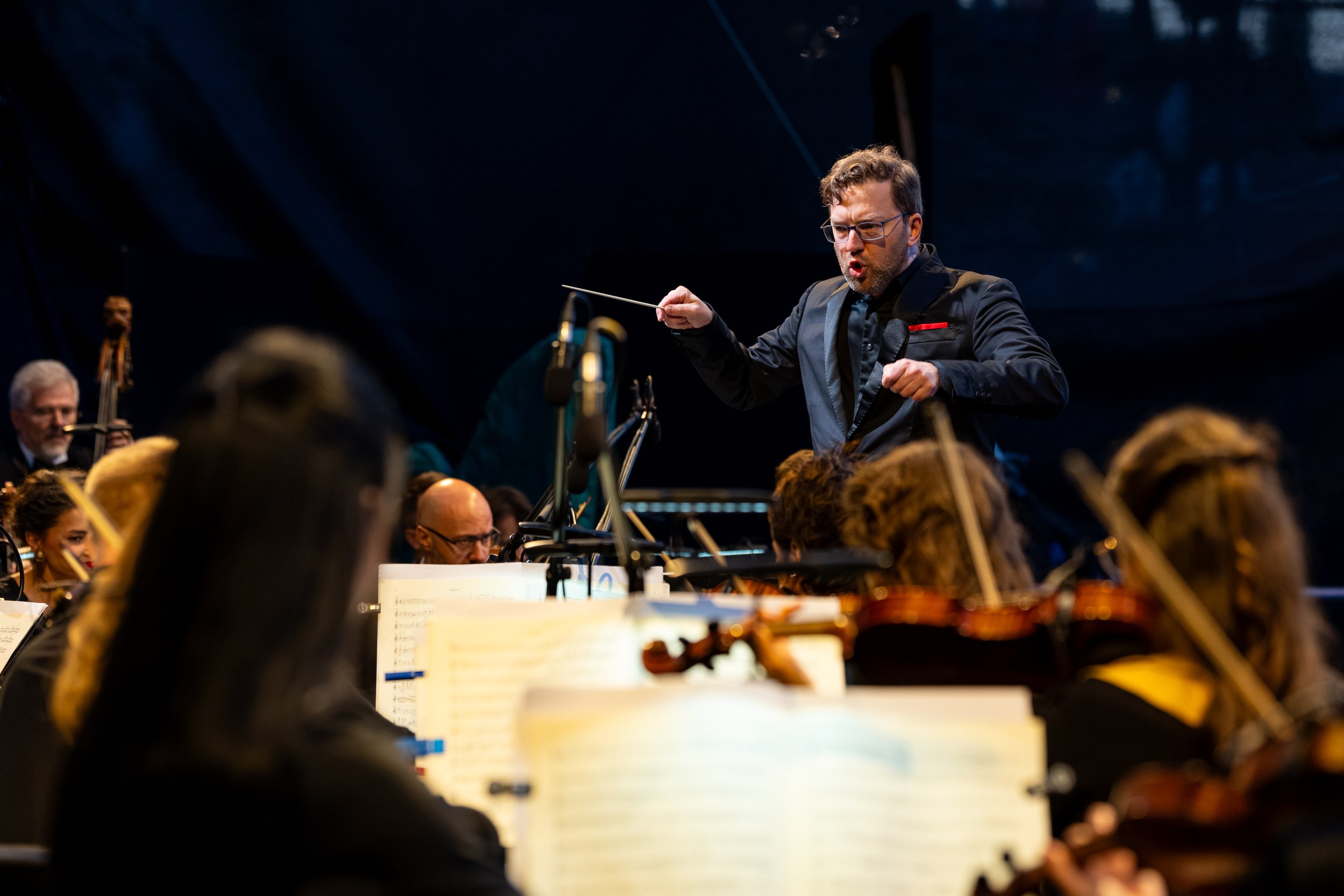 Conductor leading an orchestra during a live classical music performance