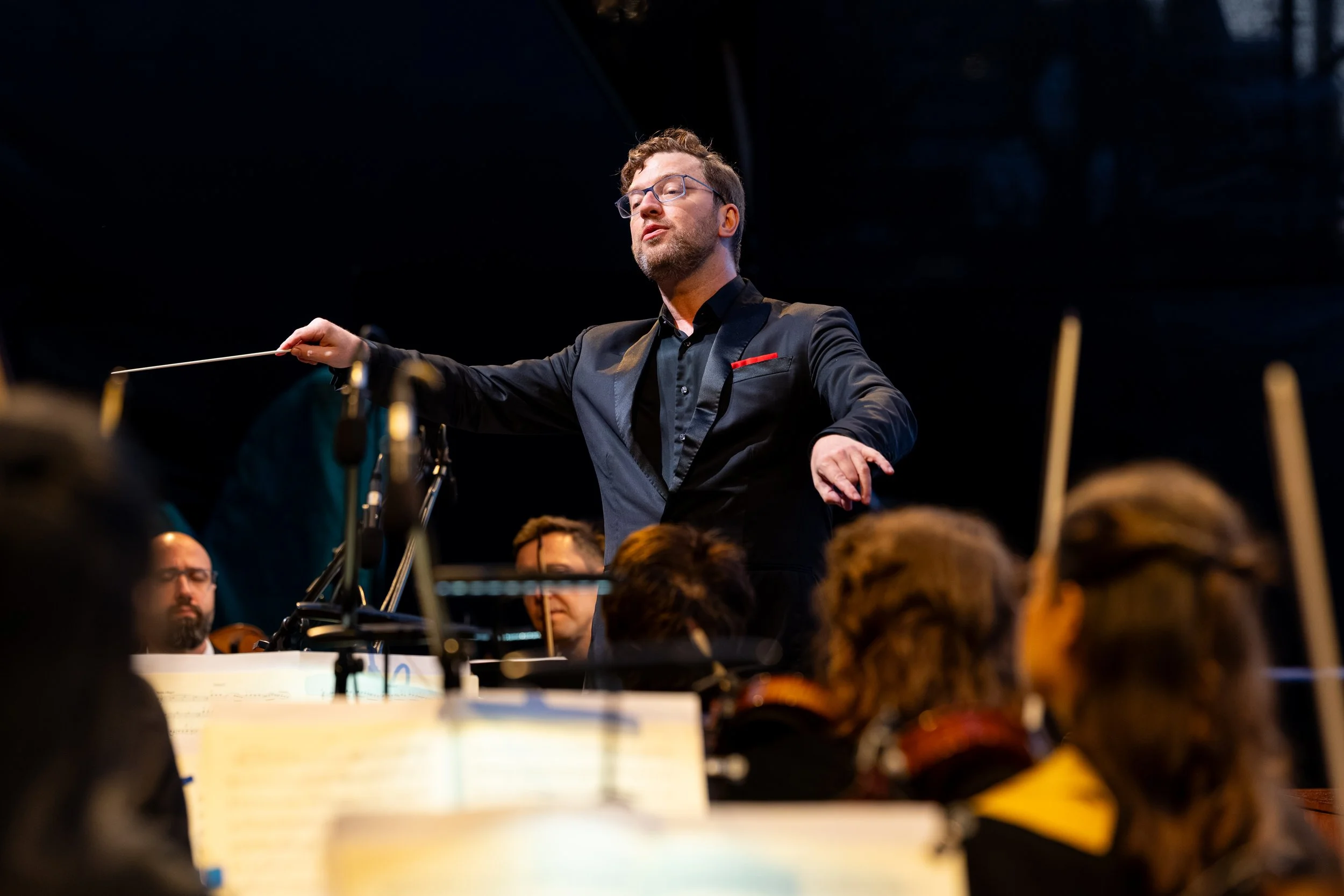 Conductor leading an orchestra with a baton during a live performance