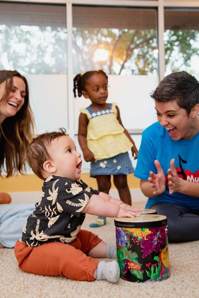 Niños pequeños disfrutando una actividad de estimulación temprana, jugando y sonriendo.