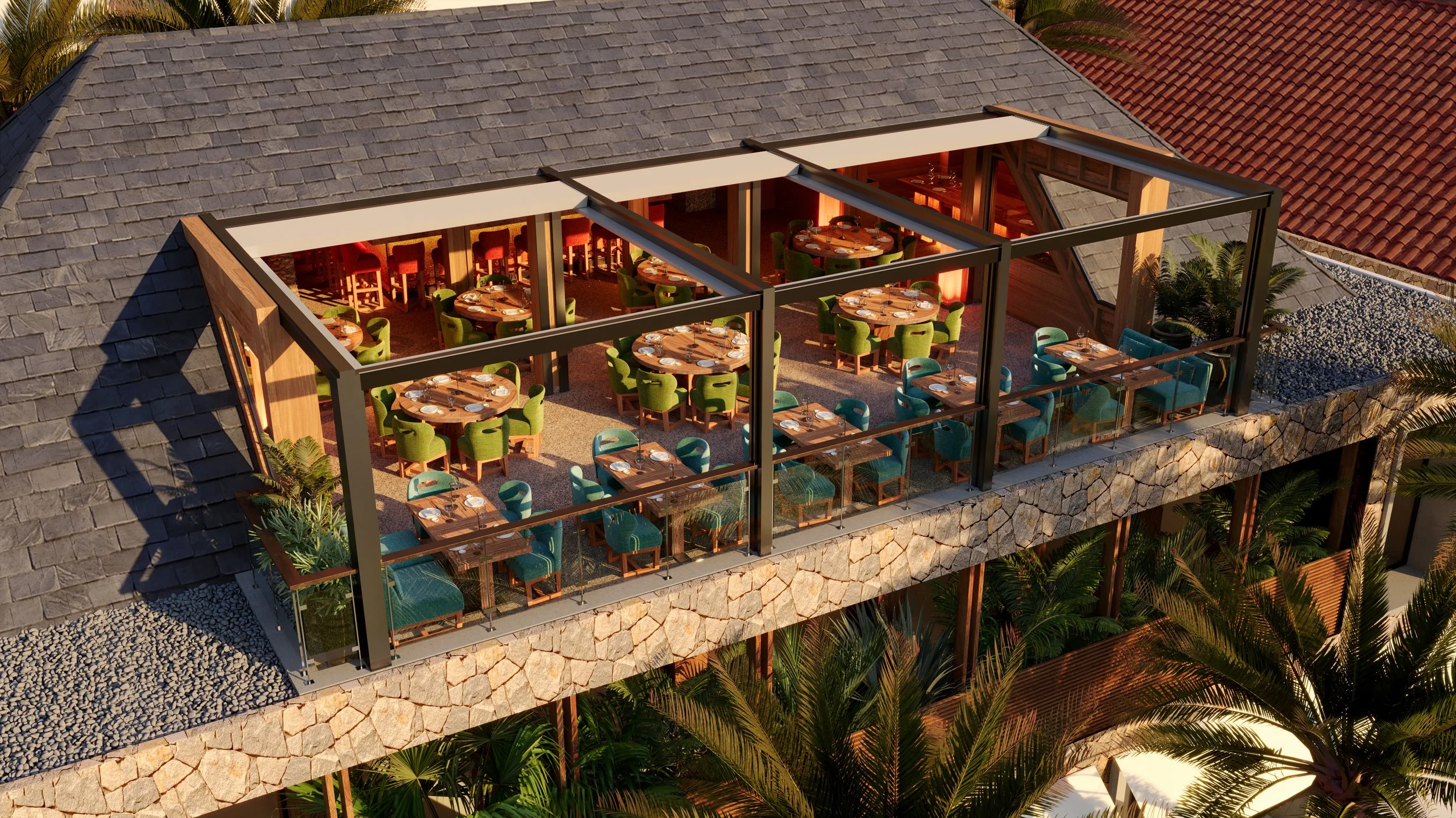 Aerial view of a restaurant rooftop with glass walls, round tables with green and red chairs, set for dining, surrounded by greenery and stone accents.