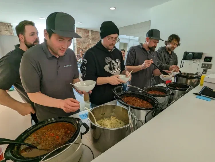 Group of people serving food from buffet trays in a commercial kitchen