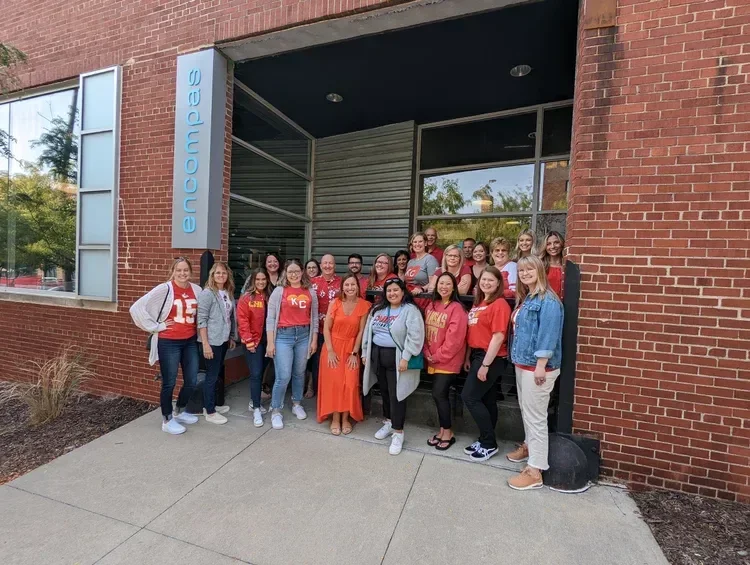 Group of employees posing outside the entrance of an Encore building
