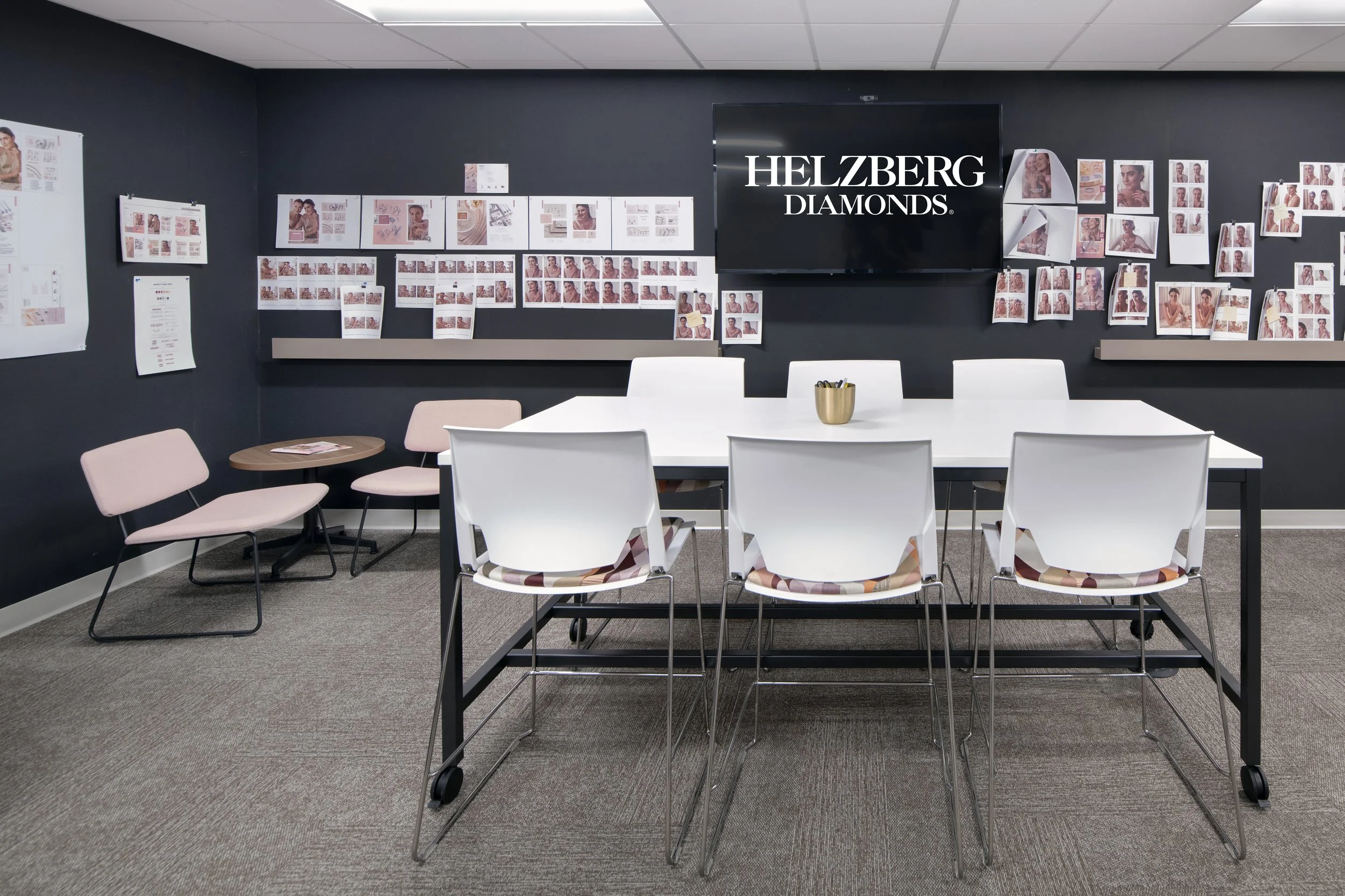 Modern meeting room with a Helzberg Diamonds display, jewelry design boards, white conference table, and chairs