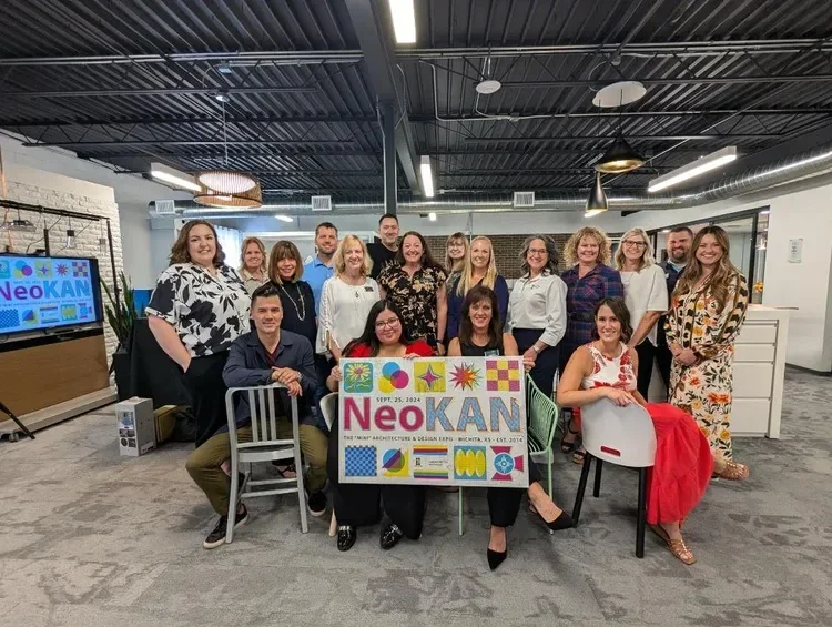 Group photo of employees holding a NeoKAN commemorative sign in a modern office