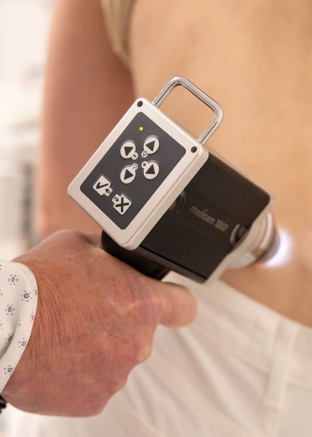 Person holding a digital blood pressure monitor cuff against their upper arm.