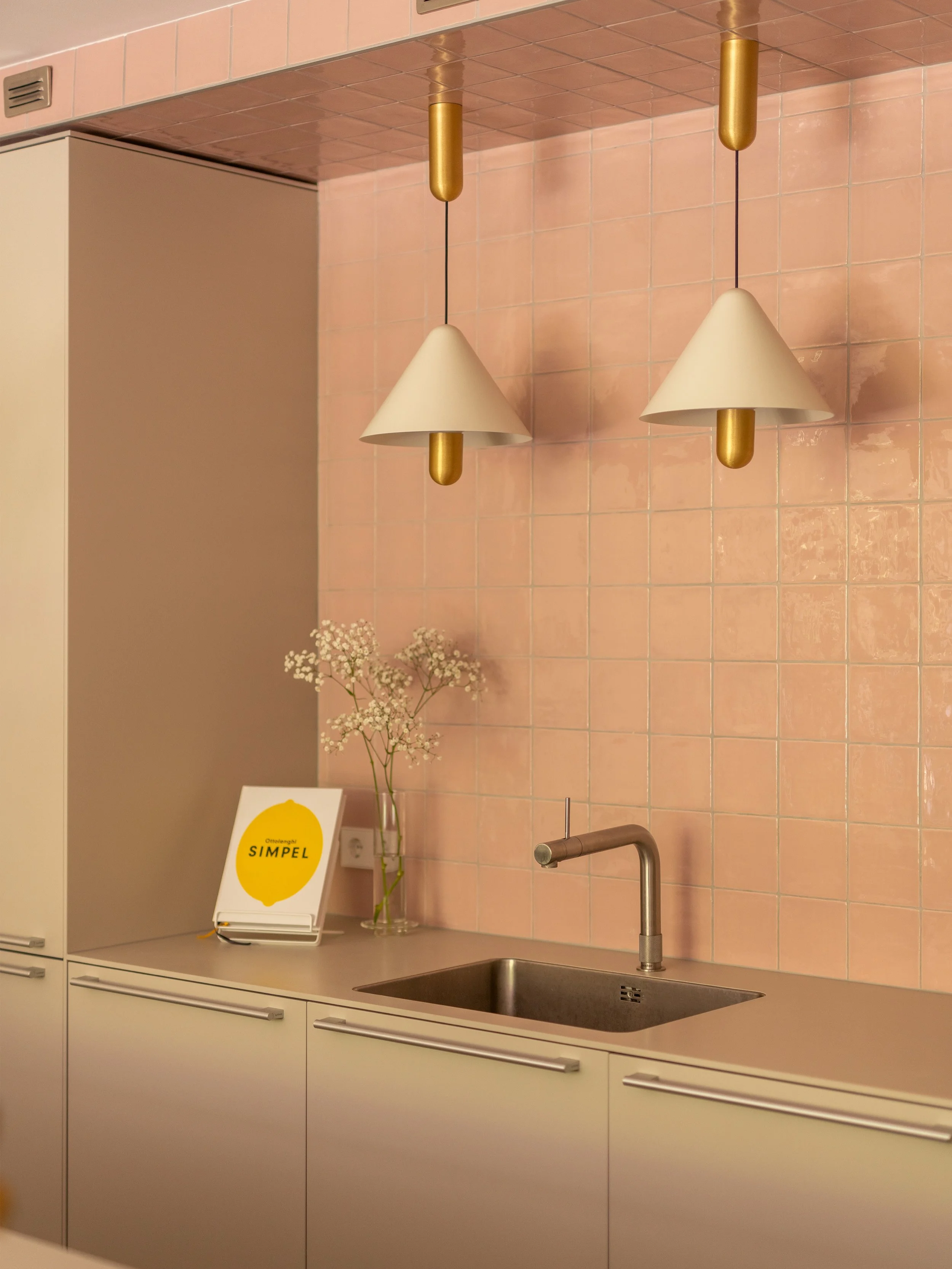 SERVE UP COLOR ~ De keuken is het hart van het huis en dat mag je zien. Zacht roze tegels tot over het plafond, messing lampen en stalen deuren met ronde grepen, ontworpen om de vierkante vormen te verzachten. Het keukeneiland biedt veel kastruimte e