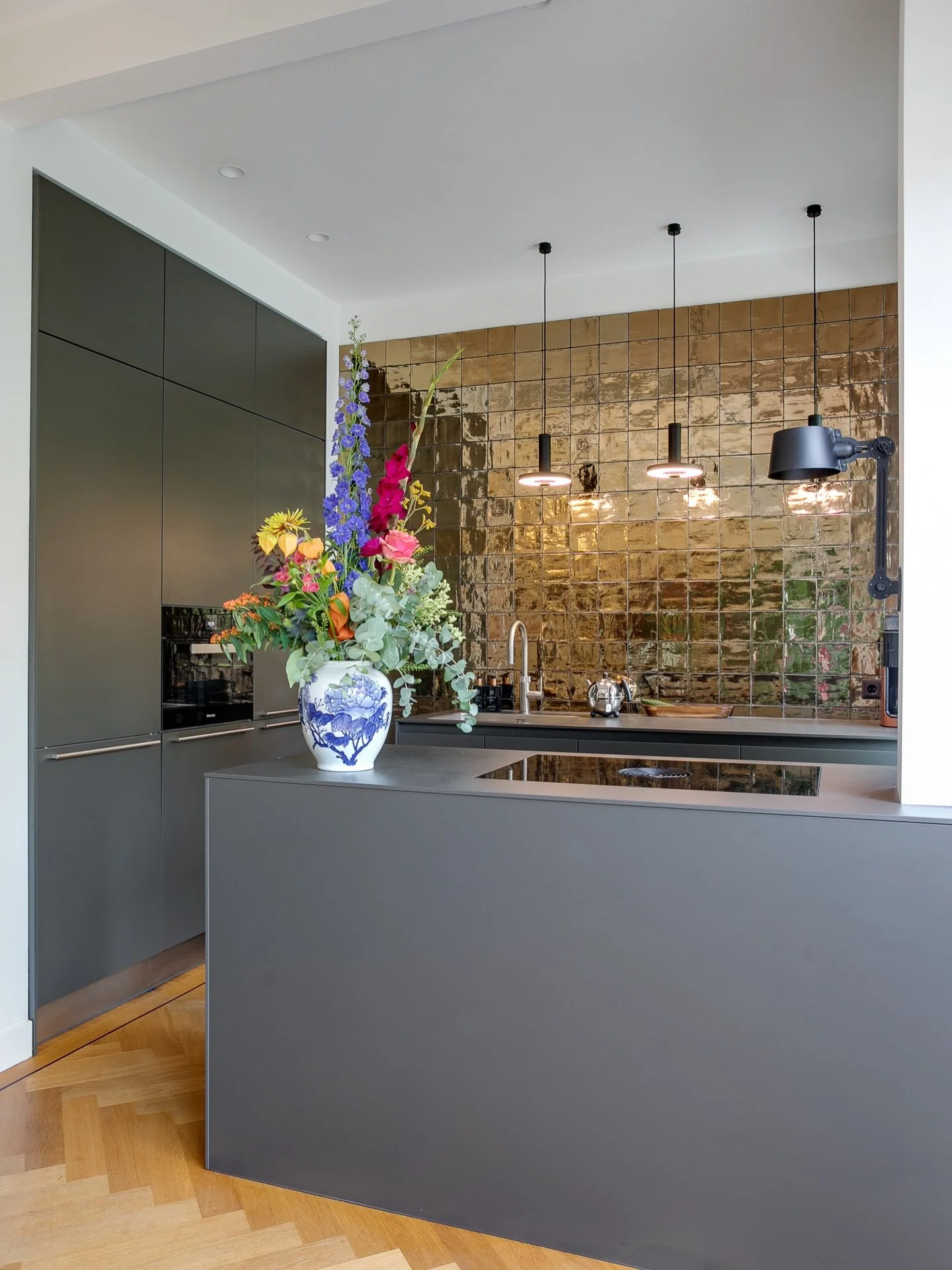 OPEN UP ~ Dit jaren &lsquo;30 herenhuis in Den Haag kreeg een open keuken die onderdeel is van de eetkamer. Het ontwerp is strak en modern, met een klassieke visgraat parketvloer met bies die de stijl van het huis op een eigentijdse manier terugbreng