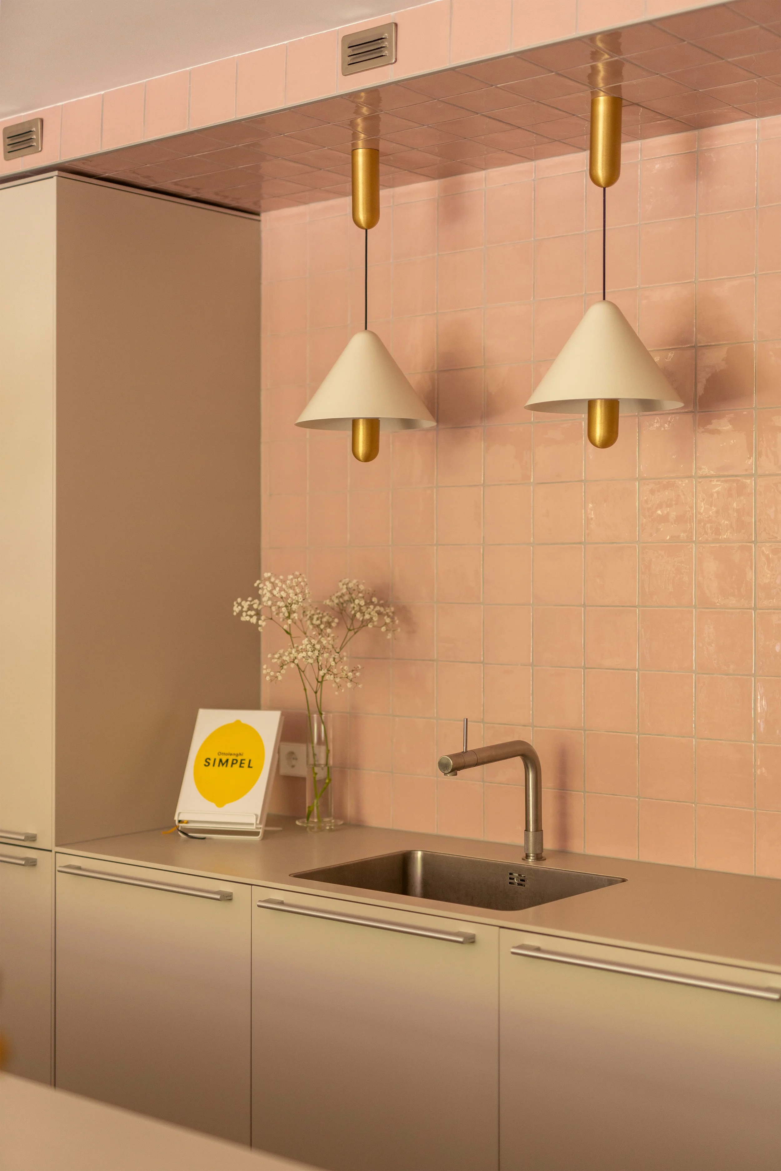 Warm en kleurrijk interieurontwerp van een luxe, high-end Bulthaup keuken met roze wandtegels, gouden designdetails en Quooker kraan in Den Haag.