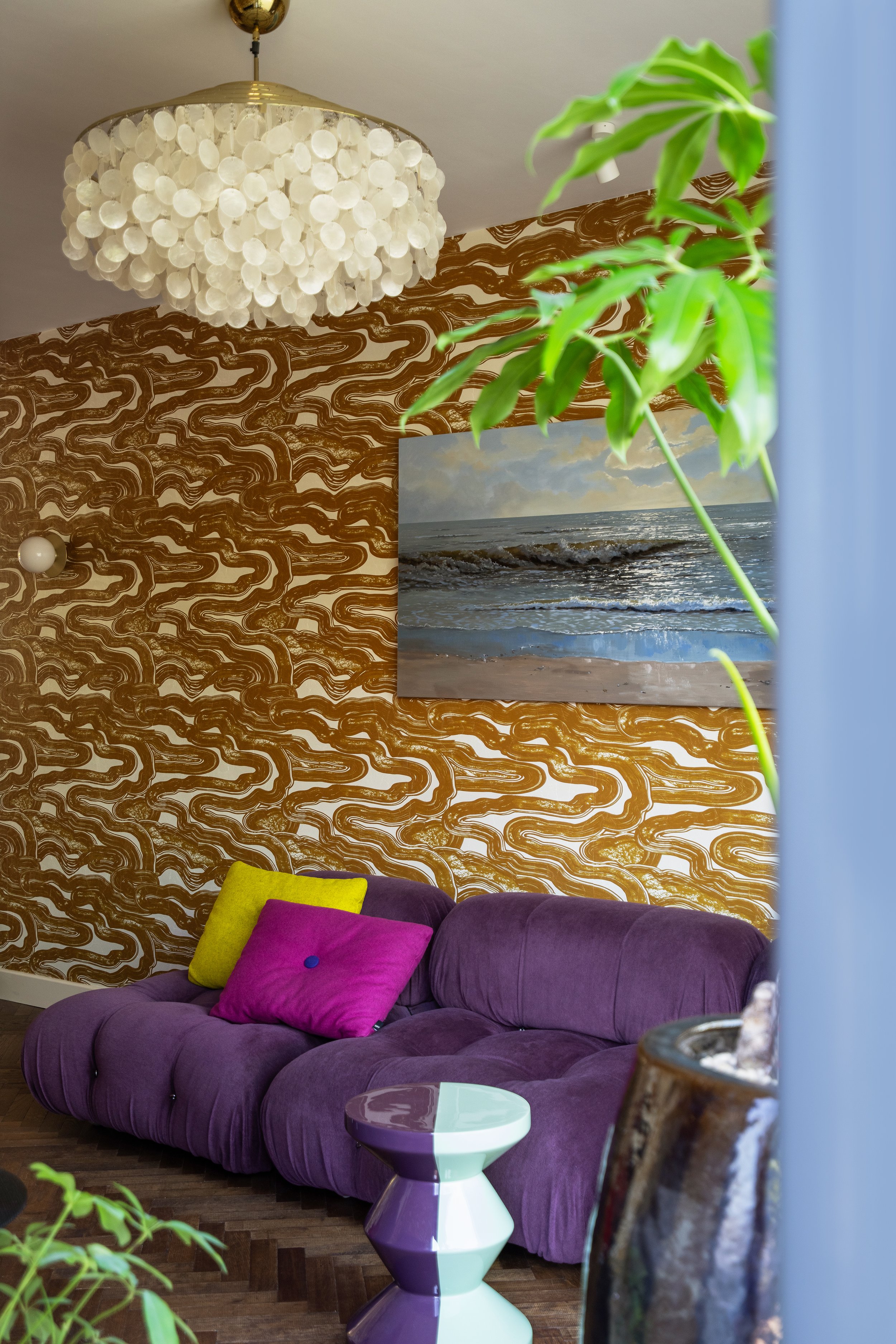 Interieuradvies van Belle & Bold, een knusse woonkamer in Scheveningen met een paarse B&B Italia Camaleonda sofa van Mario Bellini en Pierre Frey Nuages behang. 