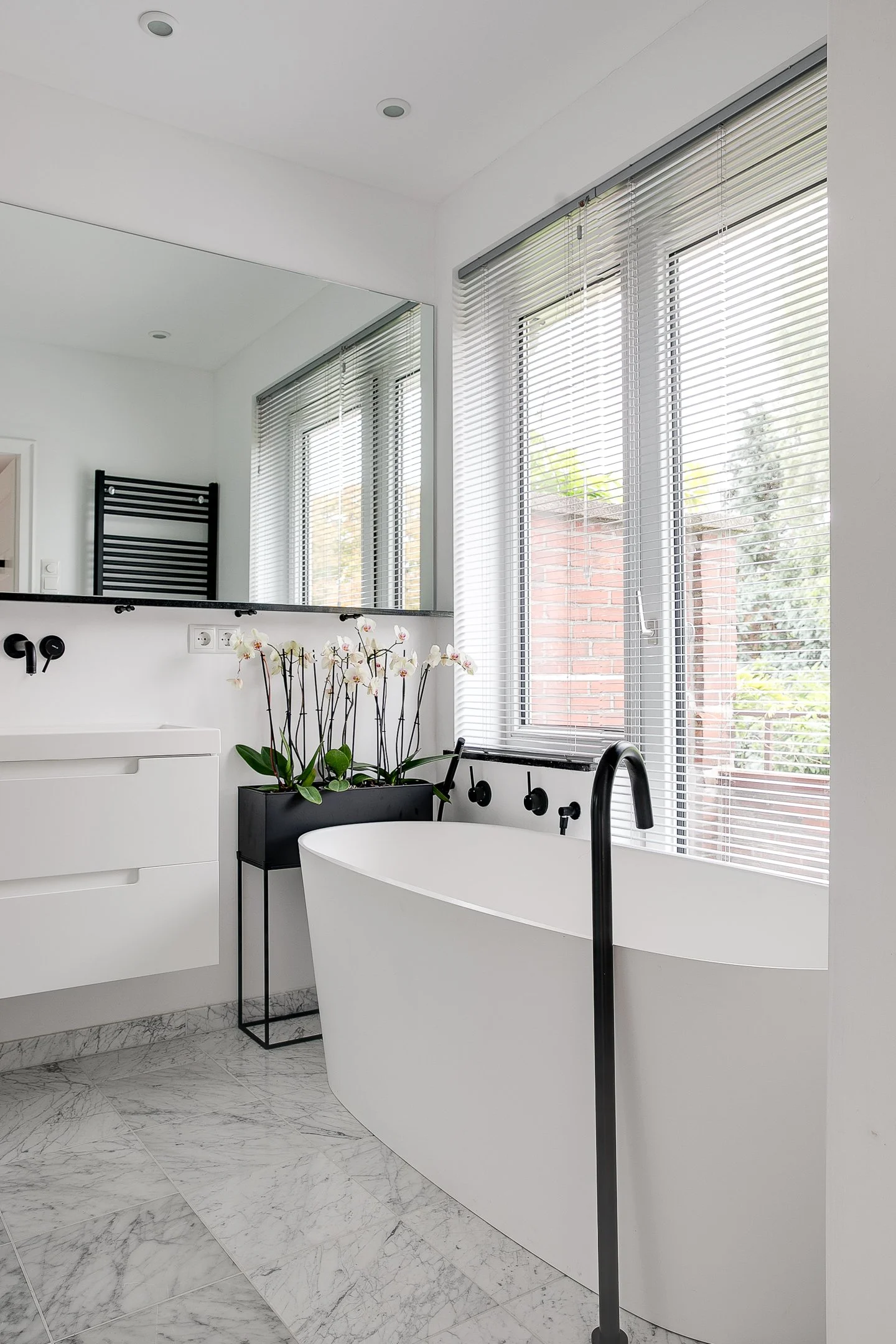 Ruime badkamer met vrijstaand bad en Carrera marmeren tegels, gerealiseerd in voormalige kinderkamer tijdens complete woningrenovatie.
