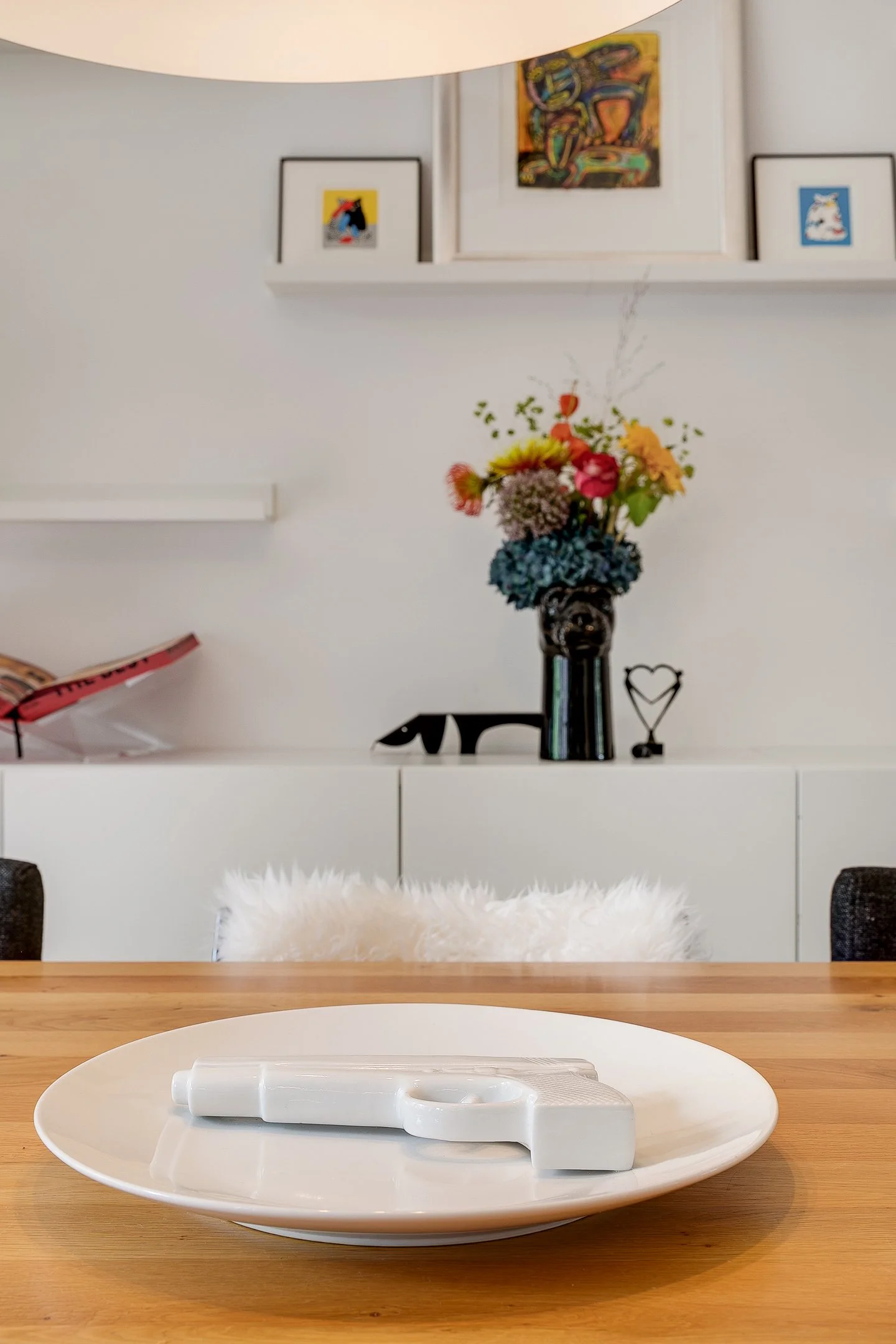 Gestylde eetkamer met een bord van Polspotten op de eiken eettafel en op de achtergrond diverse accessoires op een zwevende wandkast. 