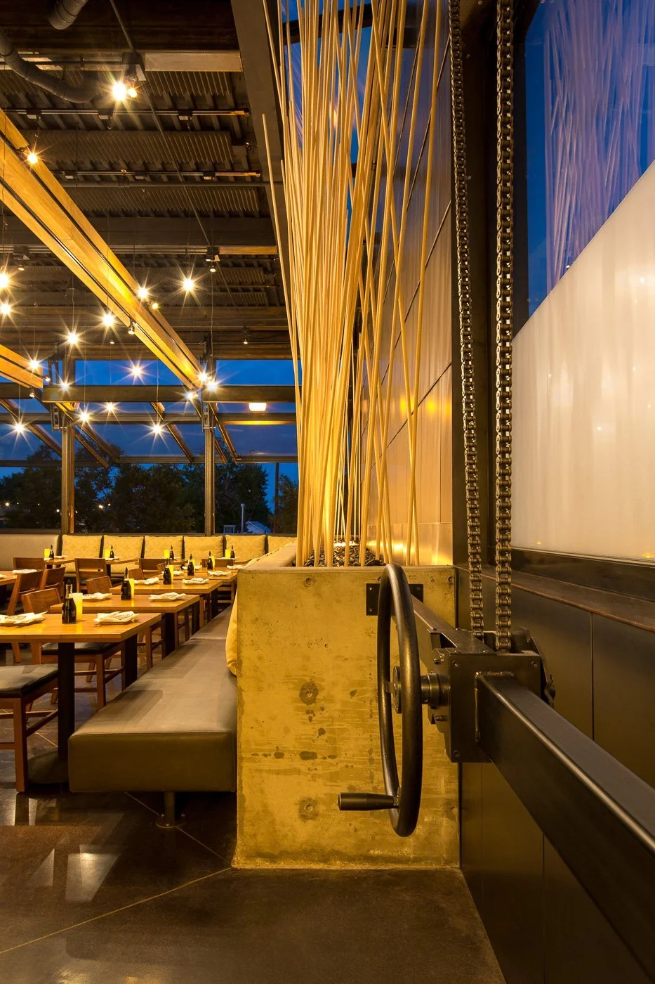 Ground-floor dining beneath a blue-lit ceiling, backlit yellow panels along the wall.