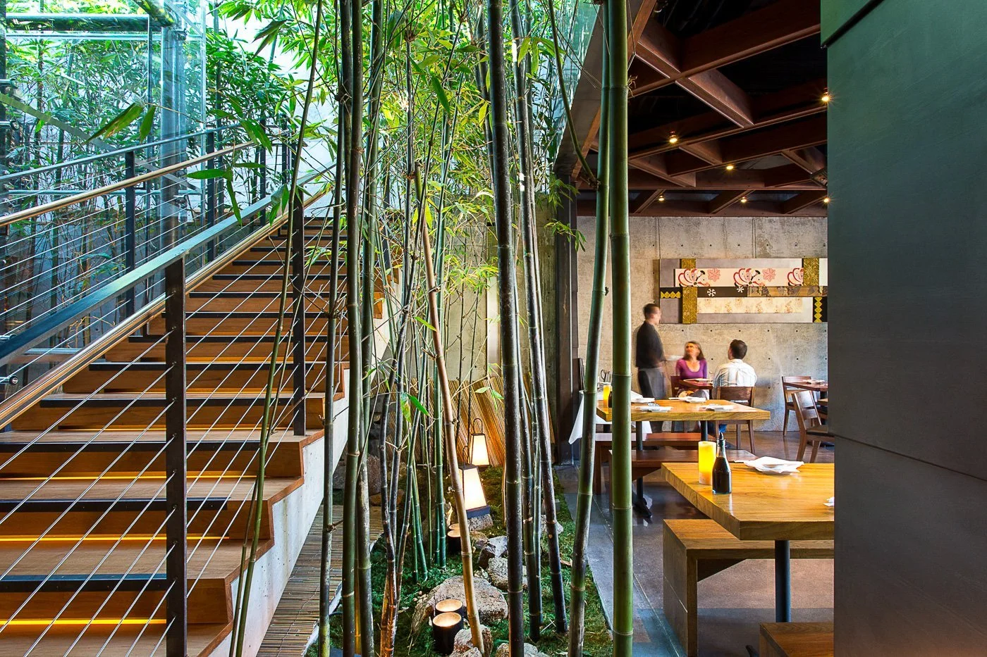 The two-story bamboo garden runs the height of the space beside the stair.