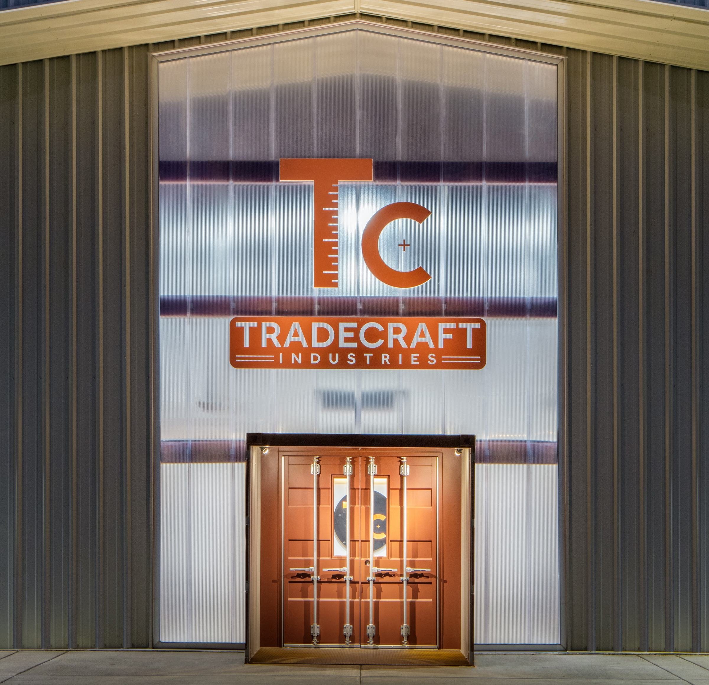 The entry is defined by glowing polycarbonate panels and a shipping container vestibule.