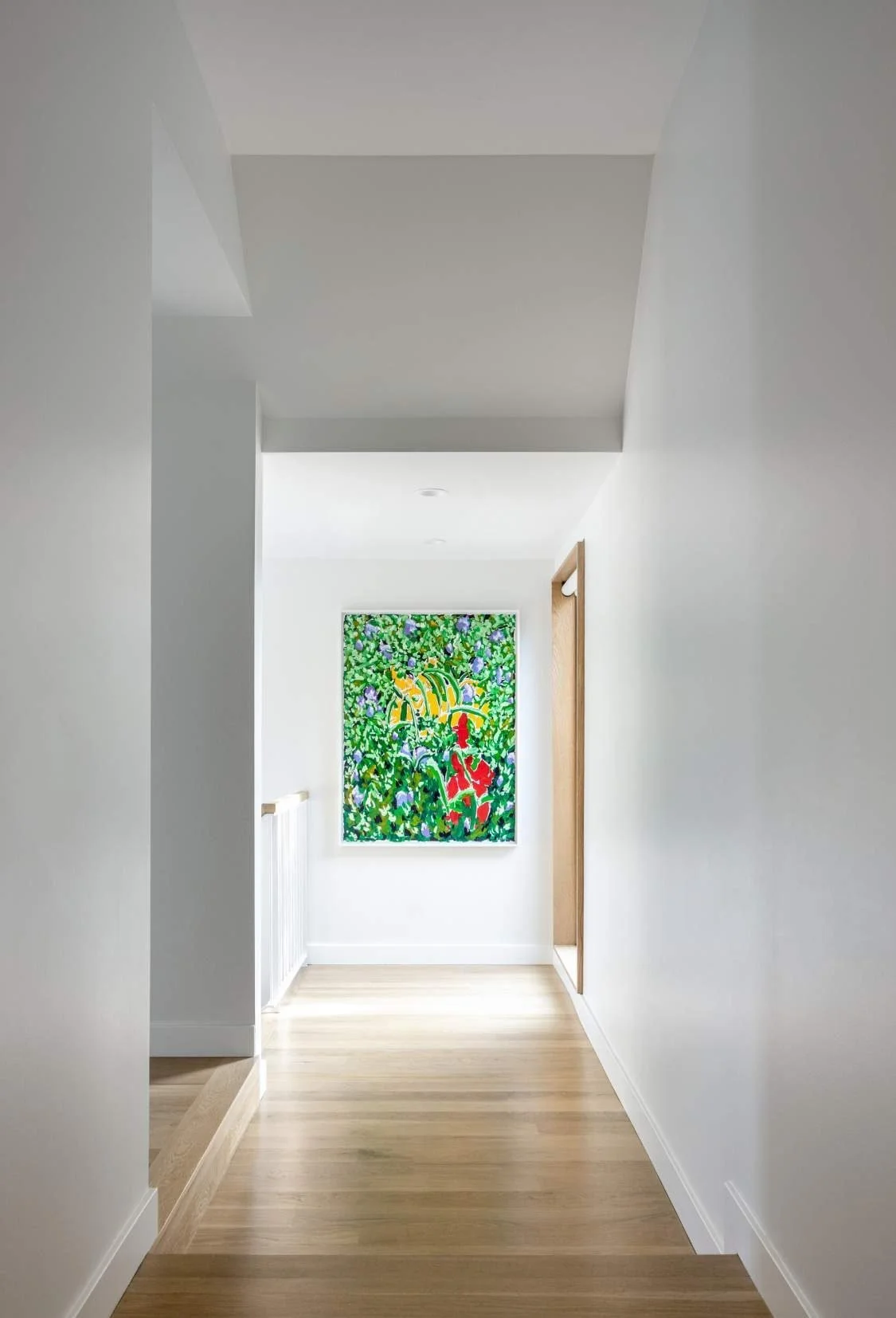 The second-floor hall, white with oak flooring, opens to the bedrooms.