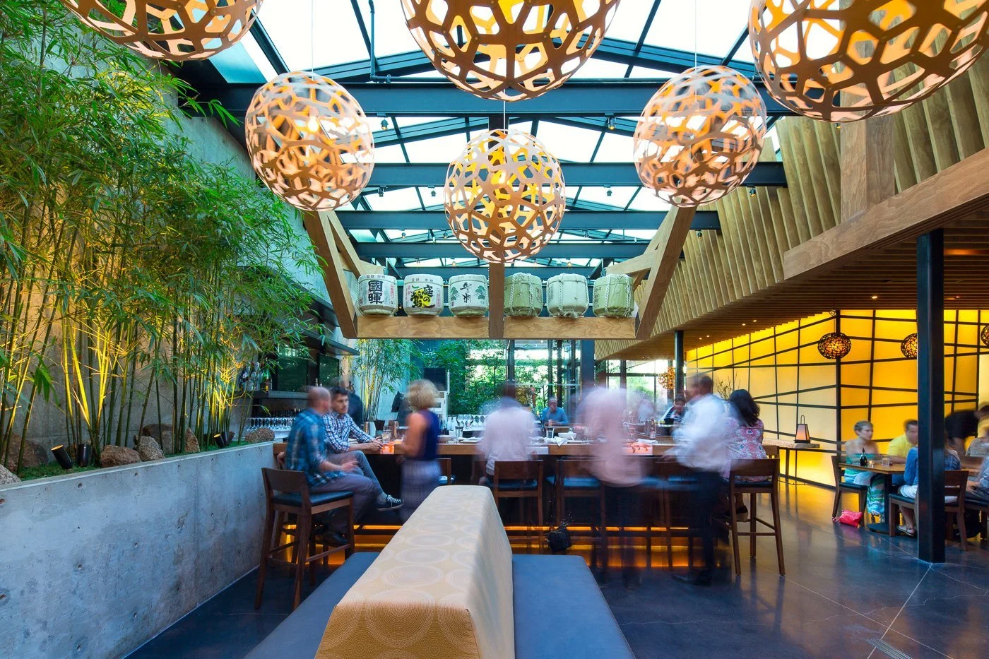 The upper dining room under the open glass roof, bamboo garden at its edge.