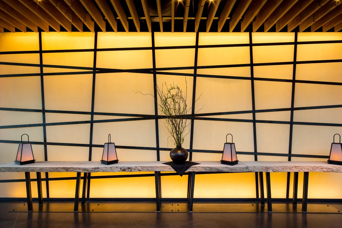 Black lattice over a backlit wall — the wabi-sabi grid, imperfect and unfinished by design.