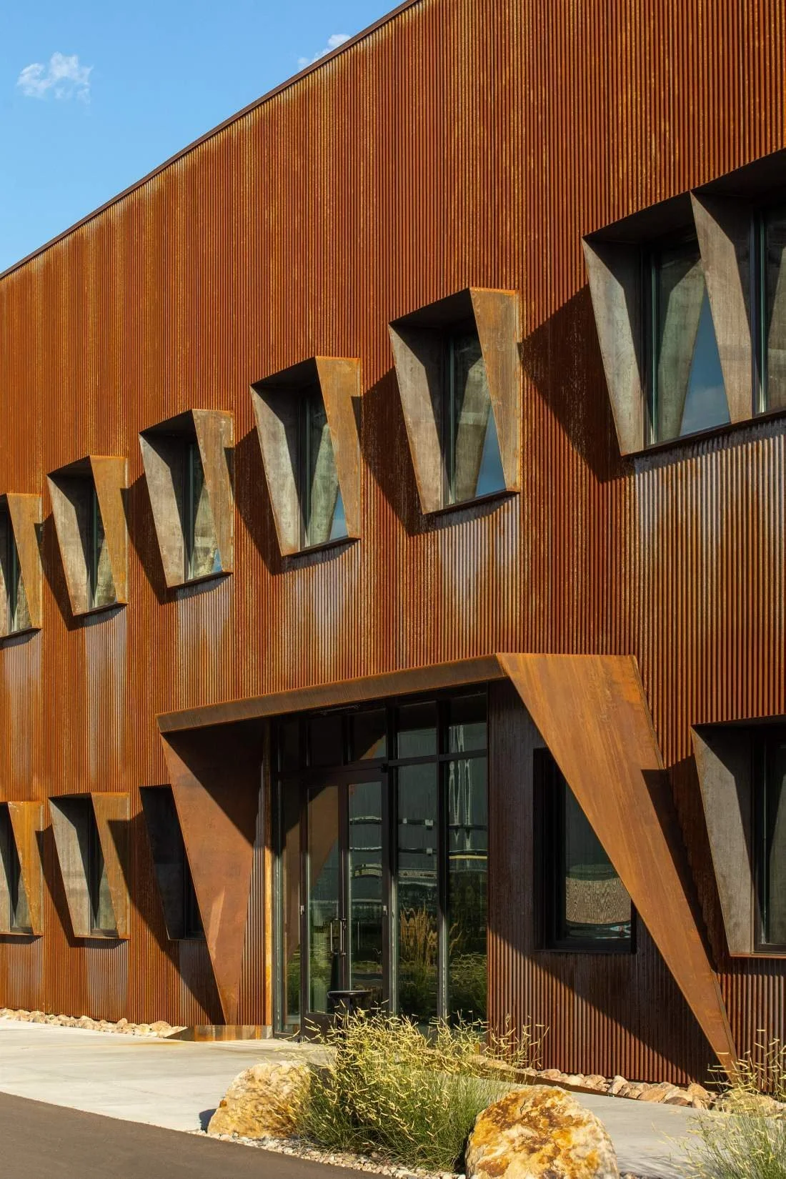 A folded corten canopy marks the glazed main entrance.