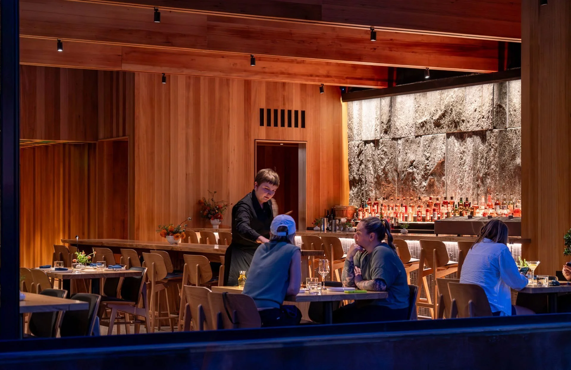 The den bar and dining room, wrapped in warm wood beneath a translucent skylight.