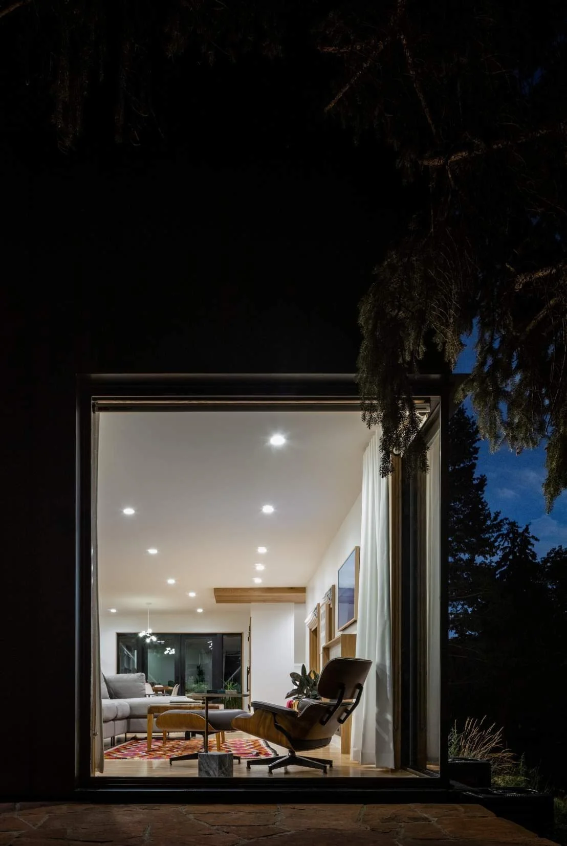 The corner window turns the living room into a lantern for the garden at night.