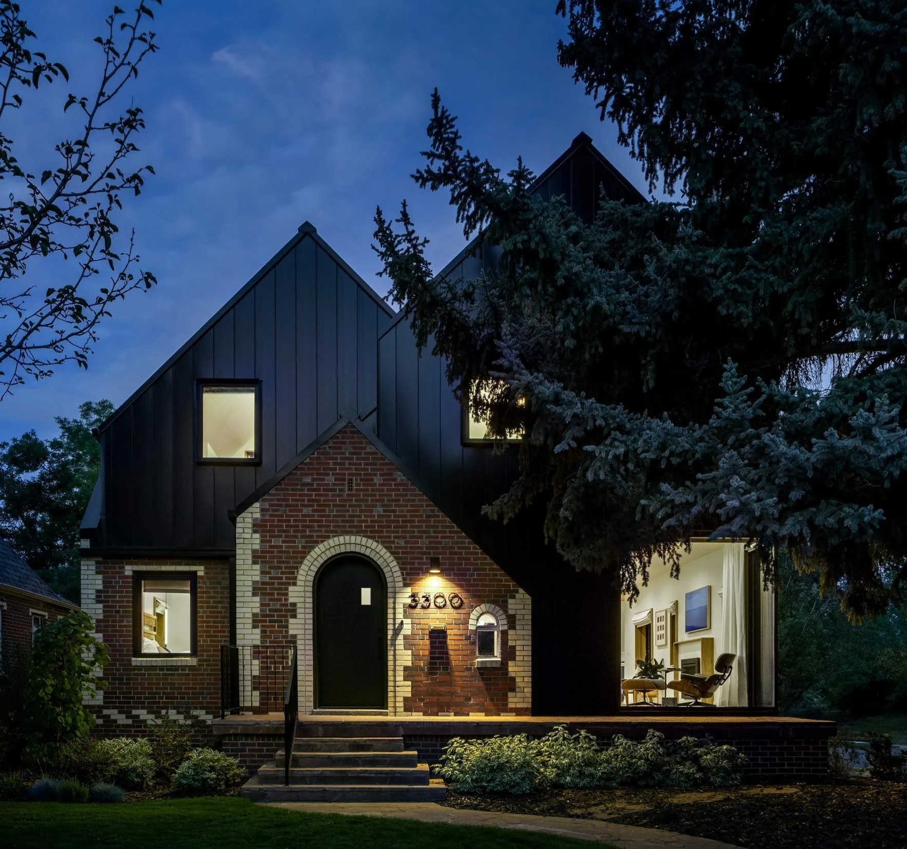 Two steeply gabled forms grow up and out from the original 1938 brick.