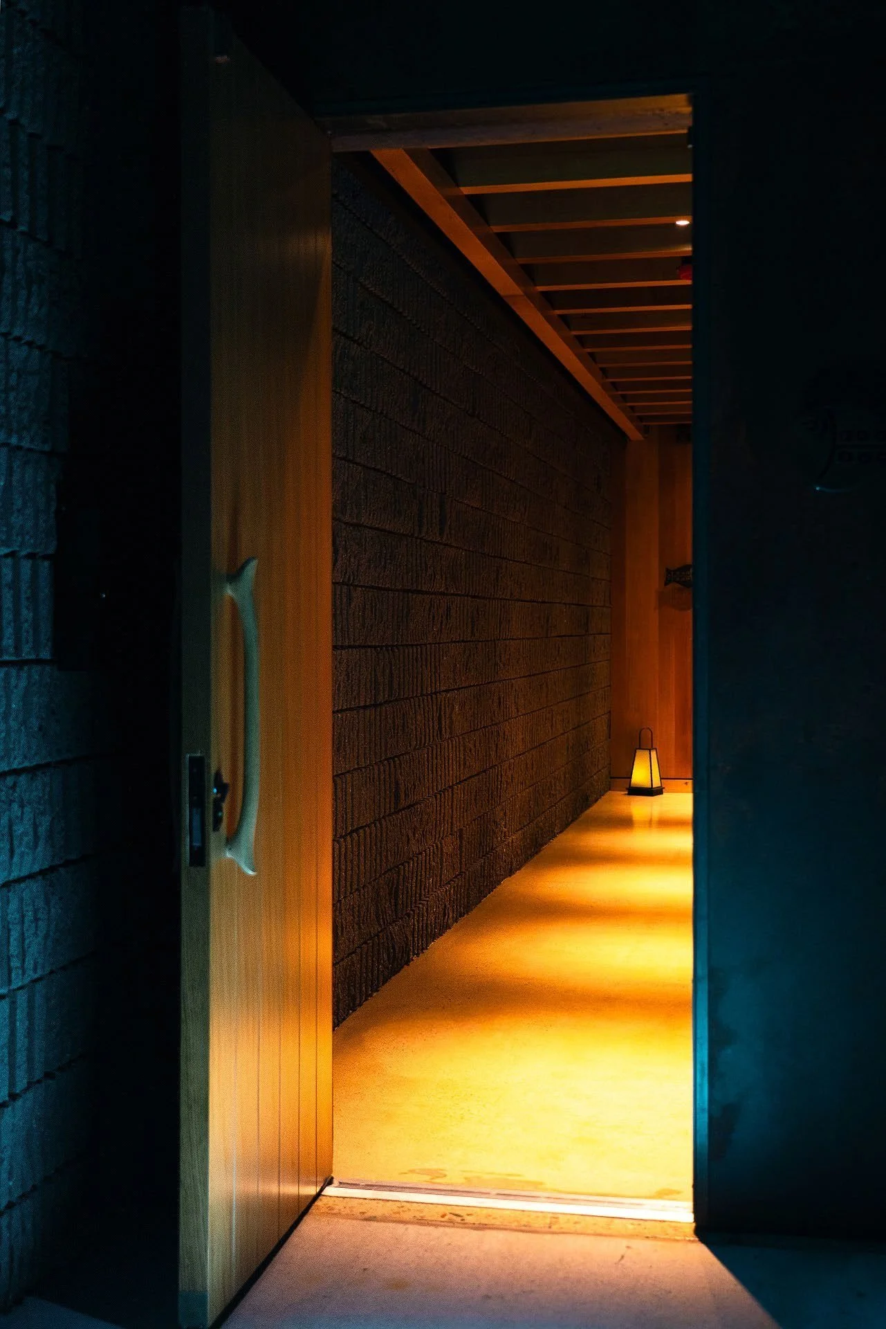 The entry threshold: a lantern-lit corridor where stone gives way to wood.