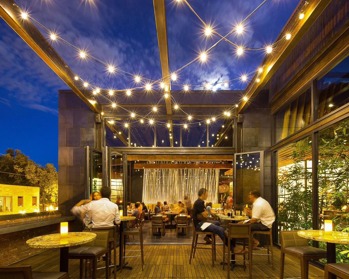 The sidewalk patio under string lights at dusk.