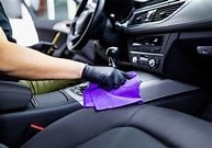 Person cleaning car interior with purple cloth