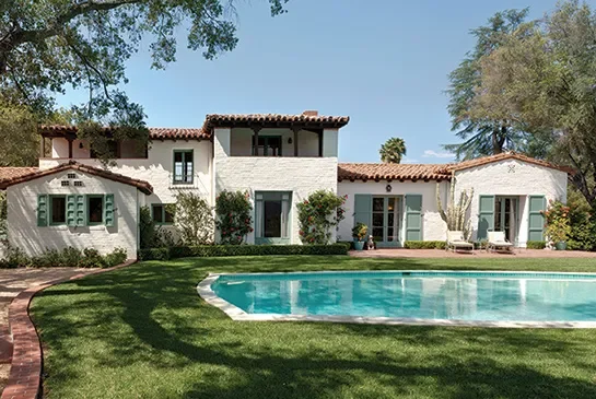 Beautiful Spanish-style house with a swimming pool and lush green lawn.