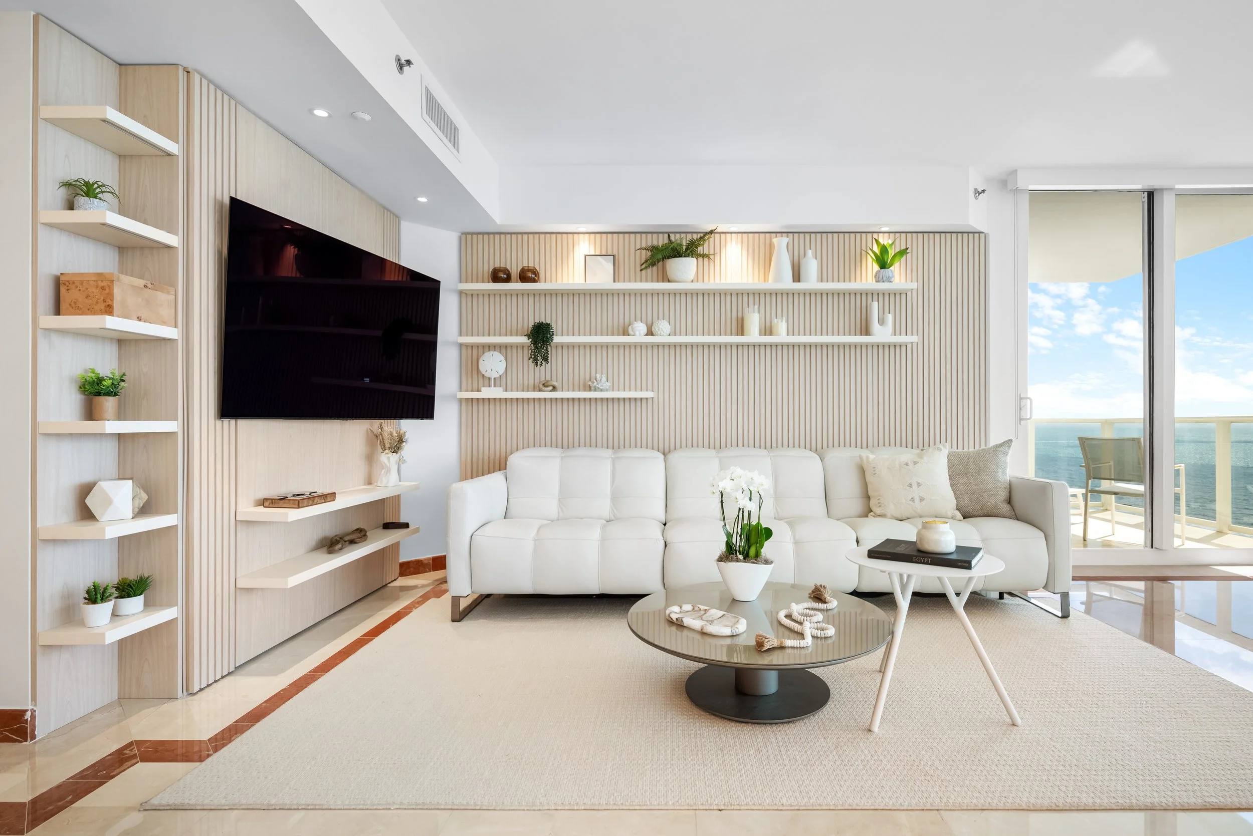 Sophisticated family room at Ocean One in Sunny Isles Beach, defined by custom wood wall paneling, layered neutral tones and soft textures that create a warm and beautifully cohesive atmosphere.