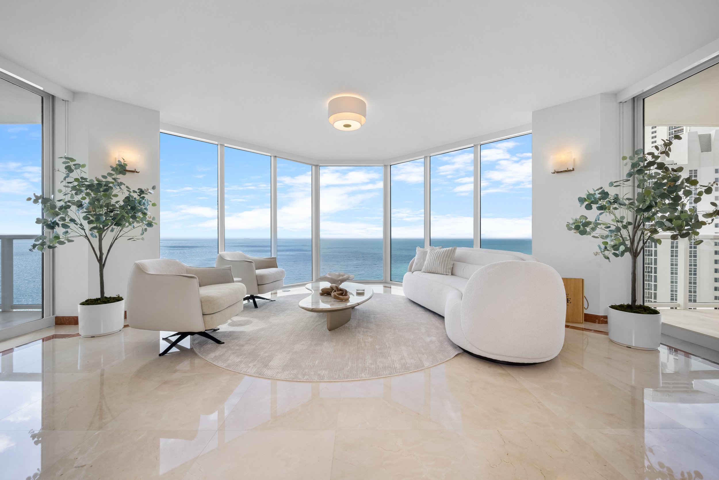 Serene living room at Ocean One in Sunny Isles Beach, where a soft neutral palette, layered textures and floor-to-ceiling windows create a seamless connection with the ocean views.