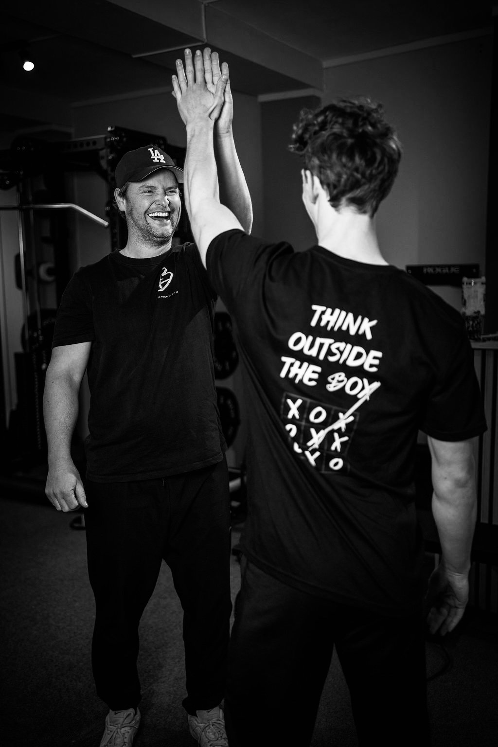 Twee mannen geven elkaar een high-five in een sportschool, glimlachend.