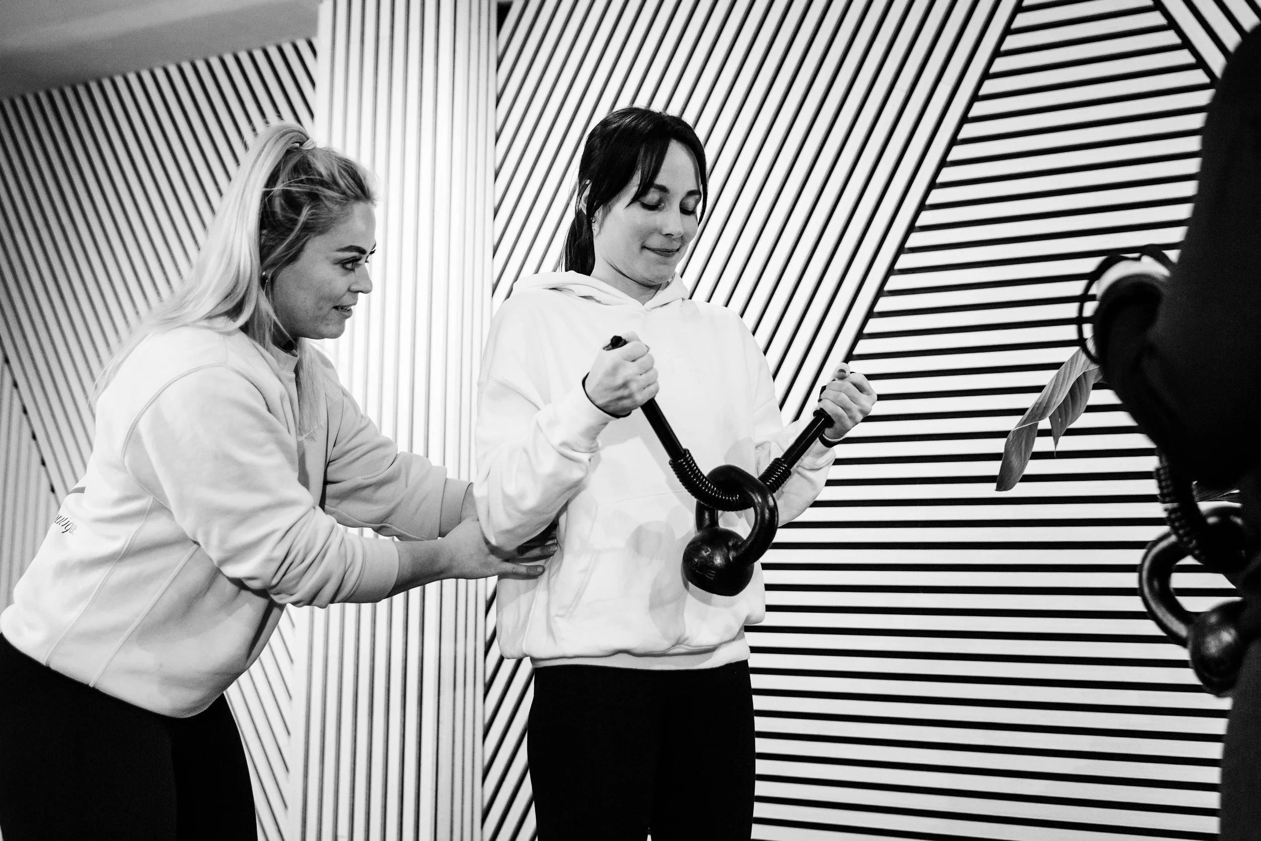 Twee jonge vrouwen trainen met fitnessapparatuur in een sportzaal.