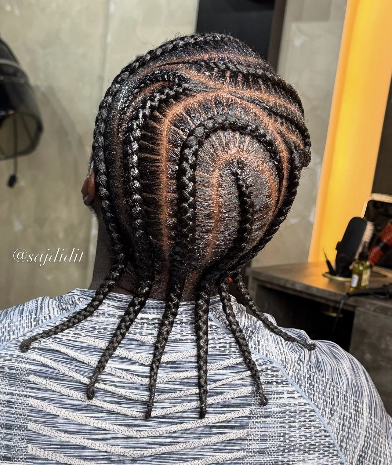 Top view of a person's head showcasing intricate, freshly done braids arranged in a spiral pattern on the scalp with shiny, well-maintained hair.