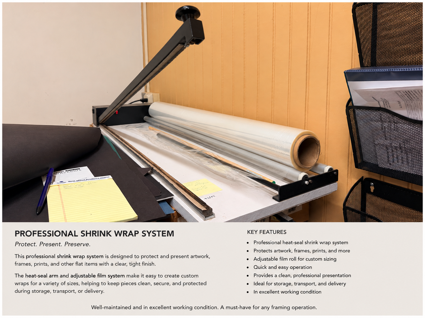 A professional shrink wrap system machine on a table, with a heat-seal arm and adjustable film roll, used for protecting artwork, frames, and prints.
