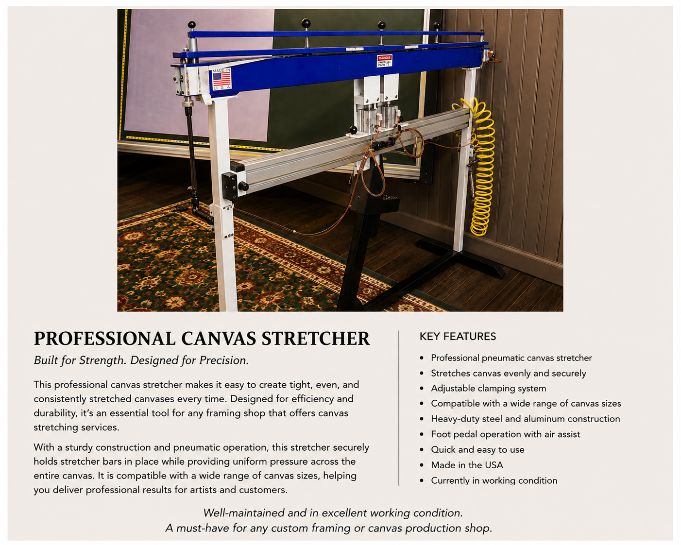 Photograph of a professional canvas stretcher machine with a blue top and metal frame, positioned in a workshop with wood-paneled walls and a patterned rug on the floor. The machine has various wires and pneumatic components.