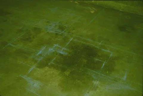 A man uses layout chalk to make a drawing on a garage floor.