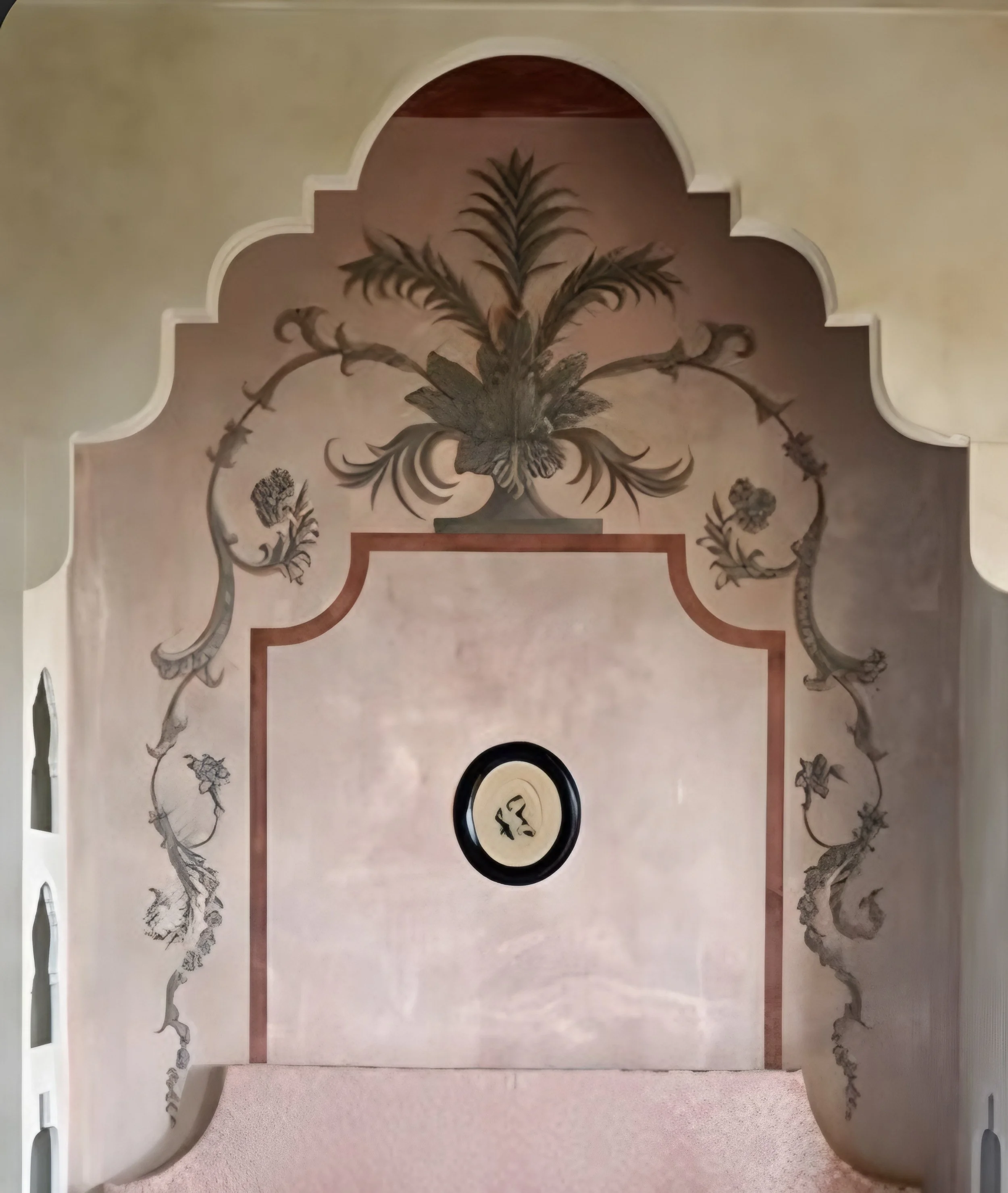 Decorative archway with a painted palm tree and floral design, featuring a circular emblem with a symbol and a rectangle with text below.