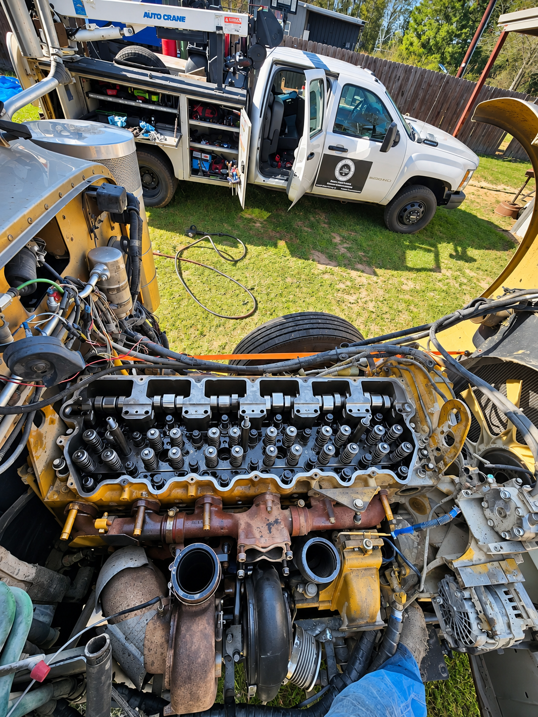 Diesel engine with its valve cover removed, with the Respect Diesel Services truck beside it.