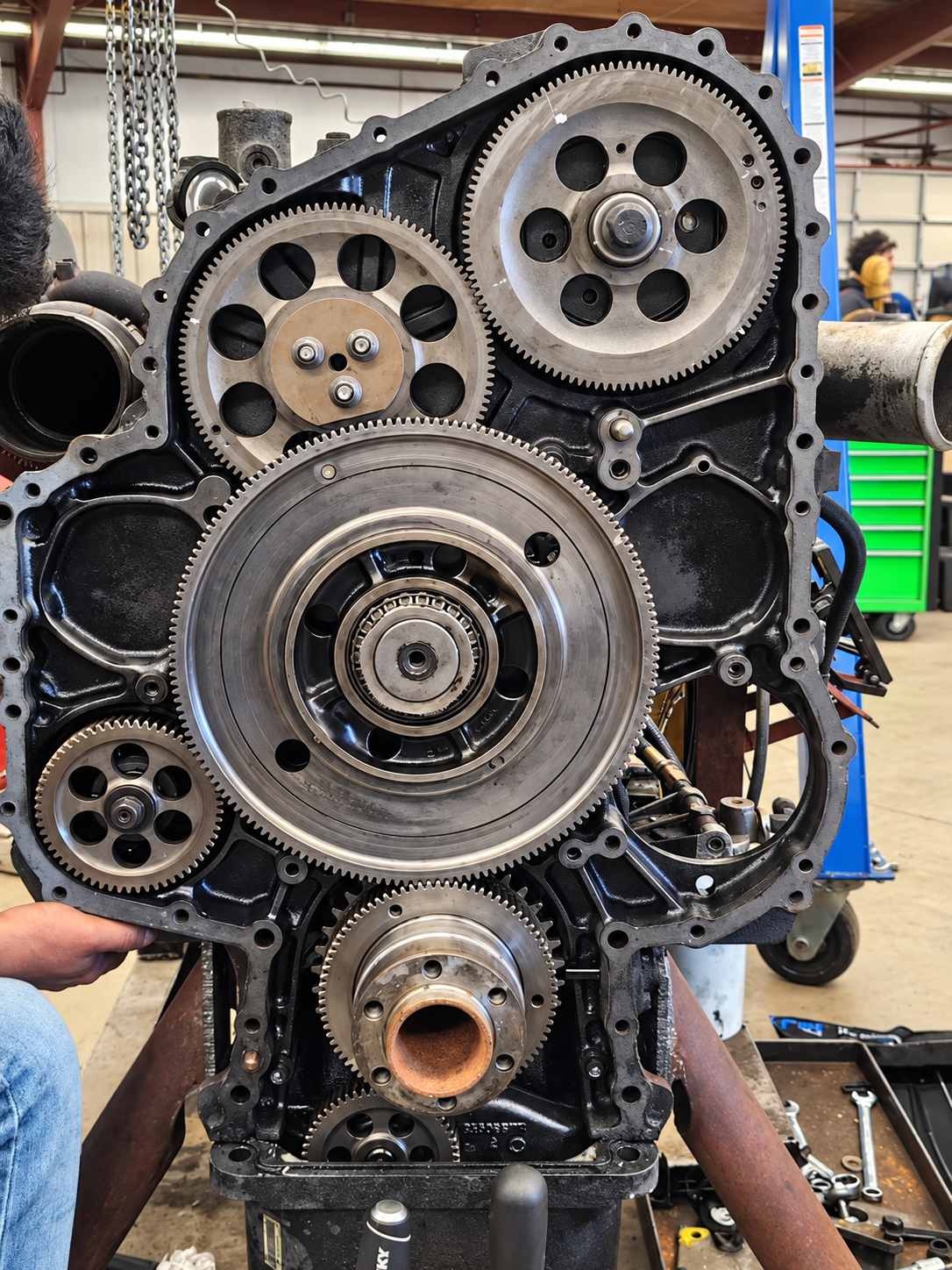 Exposed diesel engine timing gears with the front cover removed in a workshop.