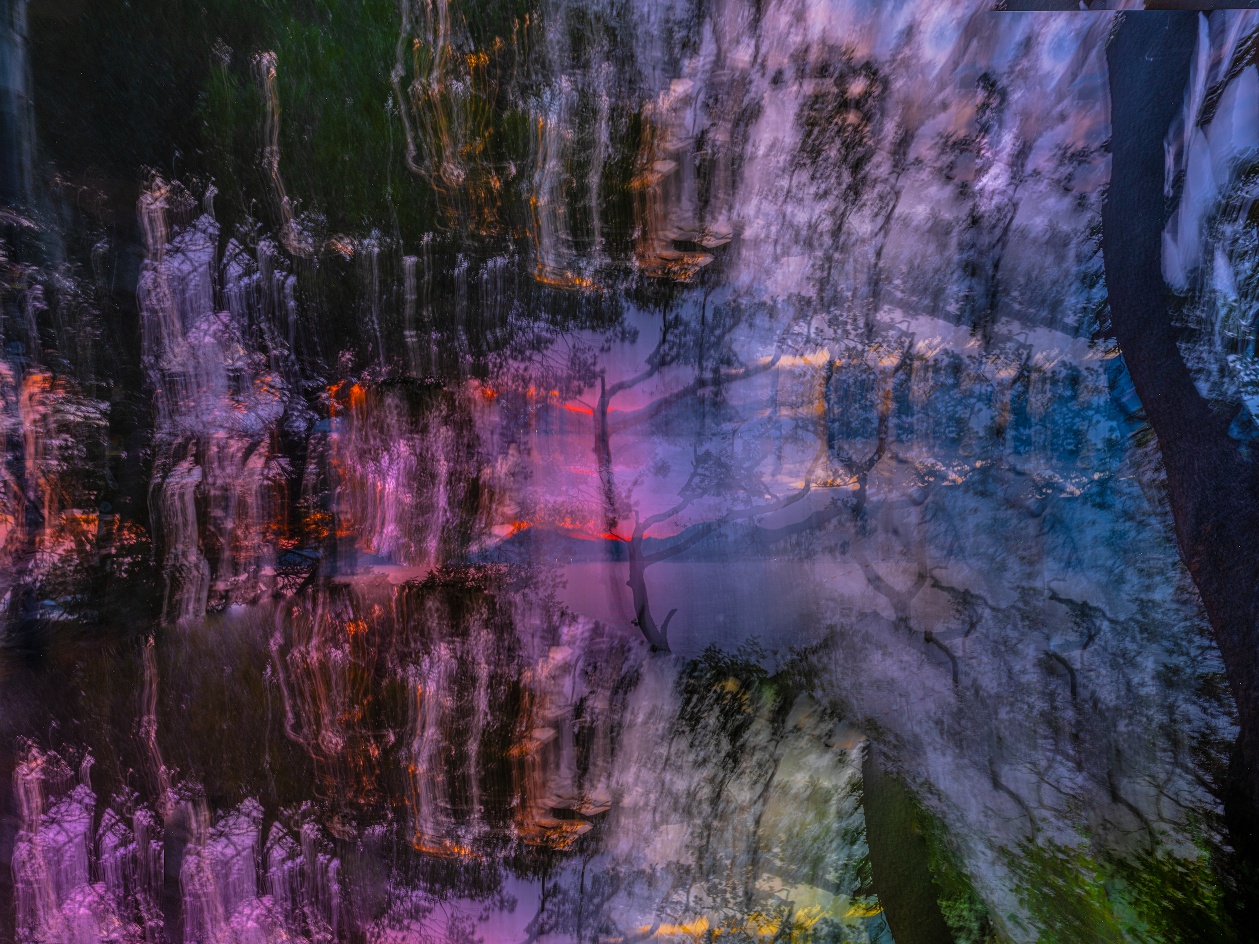 Abstract photo of a waterfall at dusk with multicolored reflections of trees and sky.