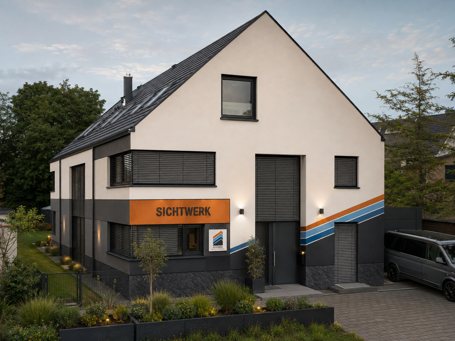 Modernes zweistöckiges Bürogebäude mit grauer und weißer Fassade, markantem orangefarbigem Schild mit 'SICHTWERK', mehreren Fenstern mit Rollläden, und umgeben von gepflegtem Garten und Parkplatz.