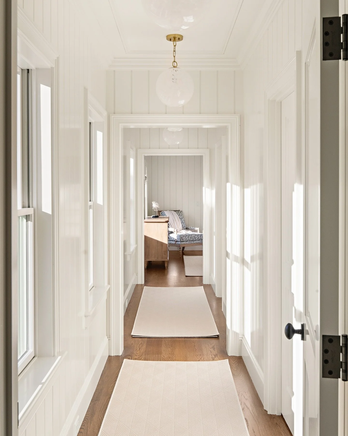 This hallway seamlessly connects to the primary suite with beadboard, custom trim, hardwood floors, and precise detailing for a cohesive flow throughout the home. 

#primarybedroom #customhome #homedesign #hallwayinspo